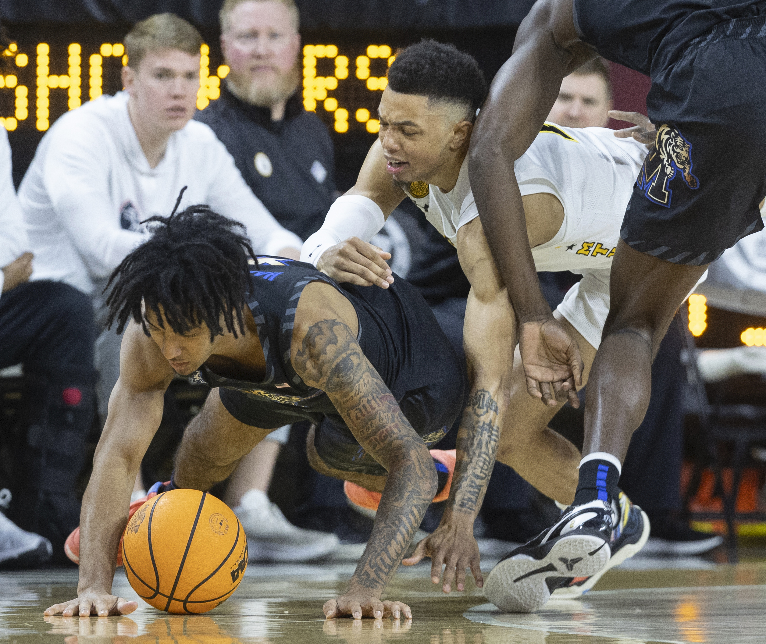 Memphis guard PJ Haggerty, left, falls to the ground with Wichita State guard Xavier Bell, middle, during the first half of an NCAA college basketball game, Sunday, Feb. 16, 2025, in Wichita, Kan. 