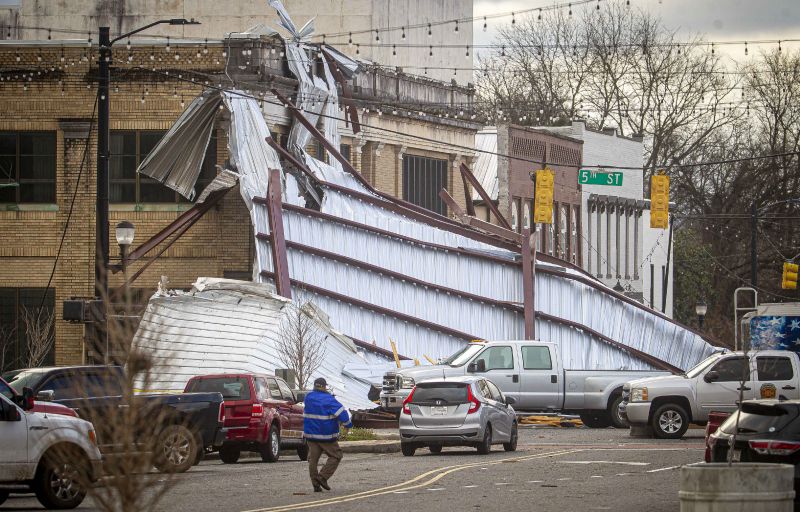 Roofing drapes over a building from a storm at the intersection of Main and Fifth Streets in downtown Tuscumbia, Ala., Sunday.