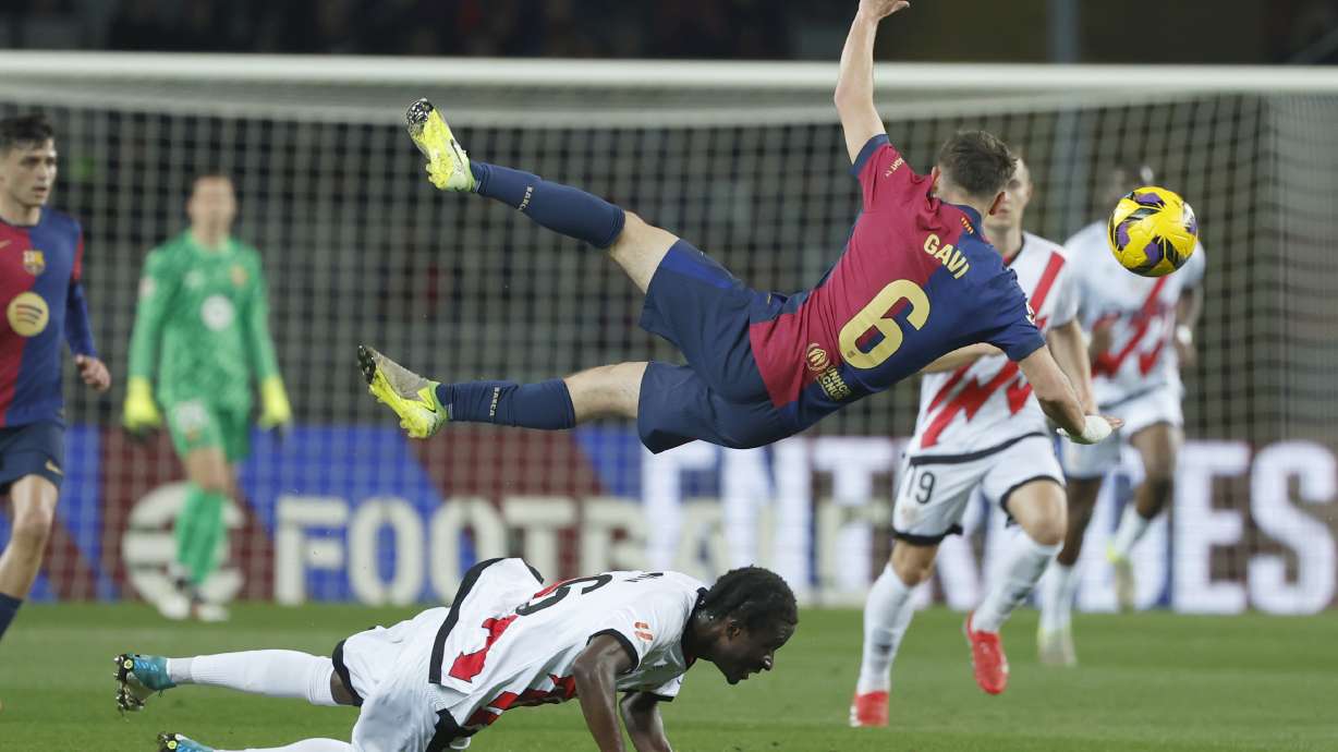 Barcelona's Gavi, centre, challenges for the ball with Rayo's Abdul Mumin, bottom, during a Spanish La Liga soccer match between Barcelona and Rayo Vallecano at the Lluis Companys Olympic Stadium in Barcelona, Spain, Monday, Feb. 17, 2025.