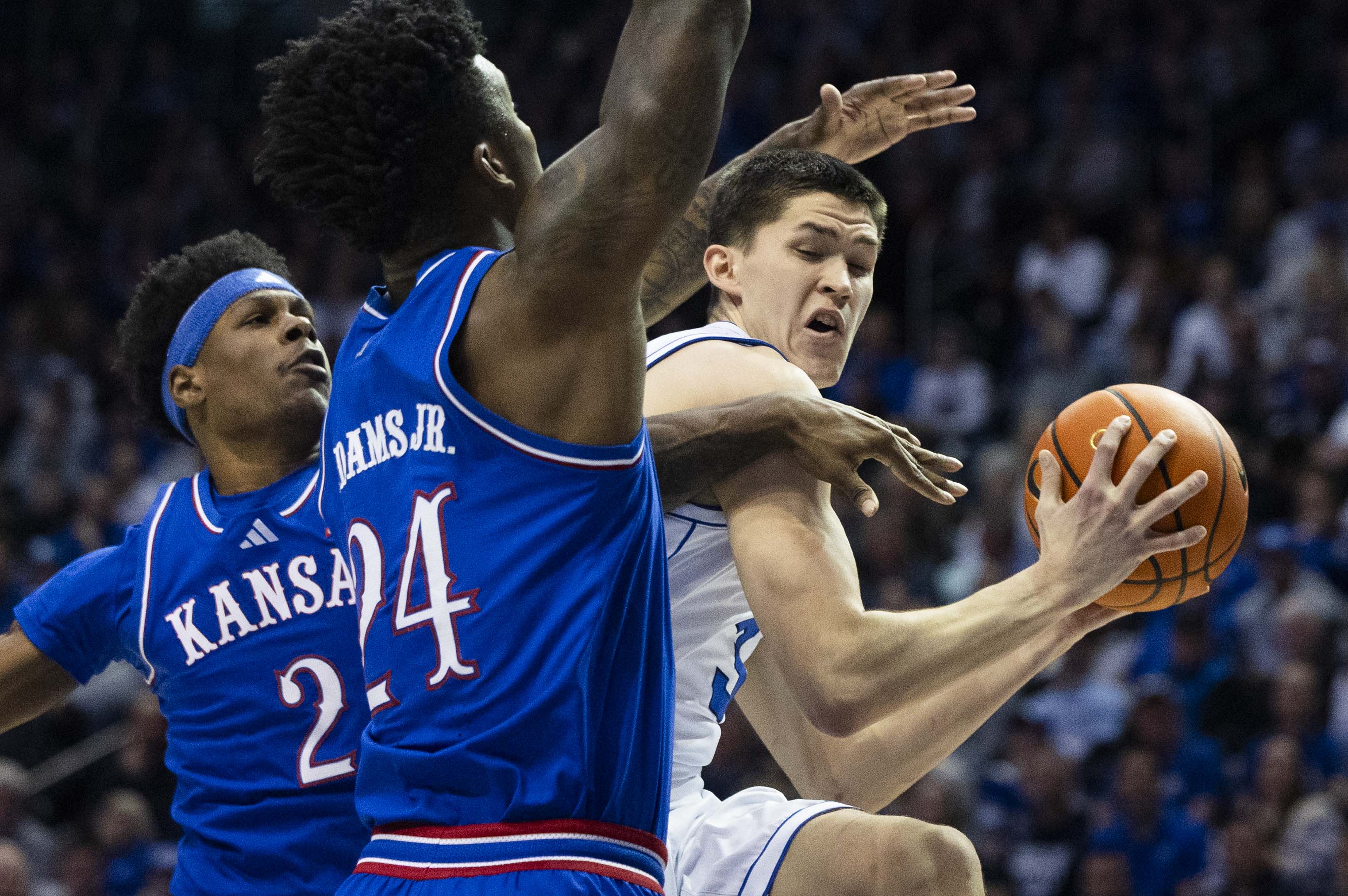 Brigham Young guard Egor Demin (3) drives to the basket while being guarded by Kansas forward KJ Adams Jr. (24) and guard AJ Storr (2) during a game between BYU and the Kansas Jayhawks at the Marriott Center on the campus of BYU in Provo on Tuesday, Feb. 18, 2025.