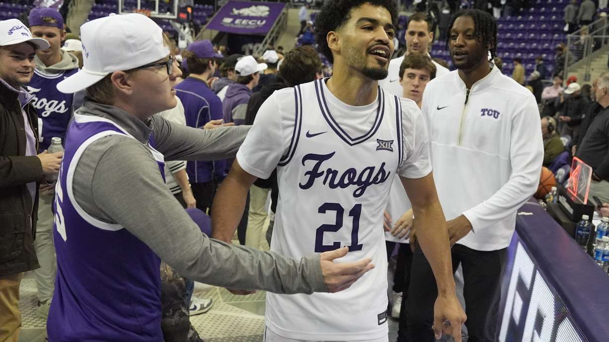 TCU guard Noah Reynolds (21) celebrates with fans on the court after the second half of an NCAA college basketball game against TCU in Fort Worth, Texas, Tuesday, Feb. 18, 2025.
