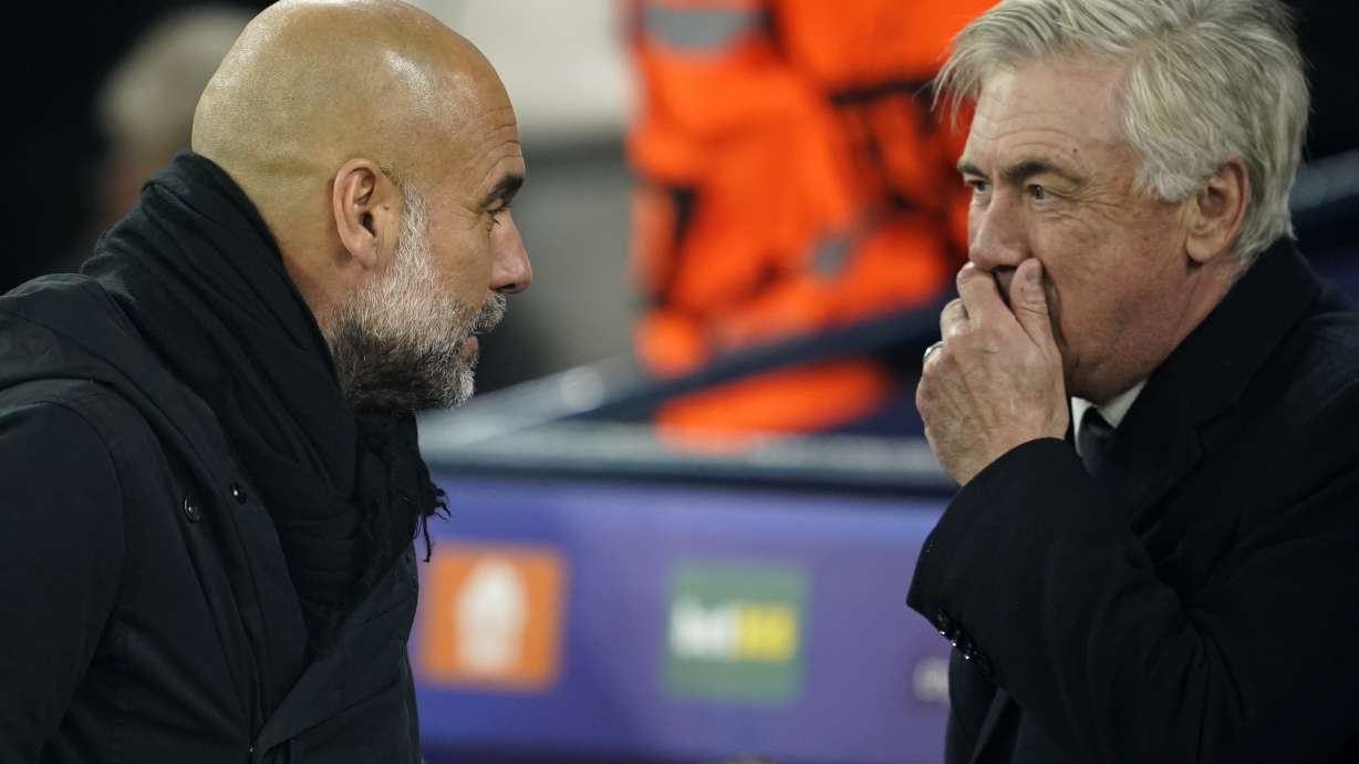 Real Madrid's head coach Carlo Ancelotti, right, talks to Manchester City's head coach Pep Guardiola before the start of the Champions League playoff first leg soccer match between Manchester City and Real Madrid at the Etihad Stadium in Manchester, England, Tuesday, Feb. 11, 2025.