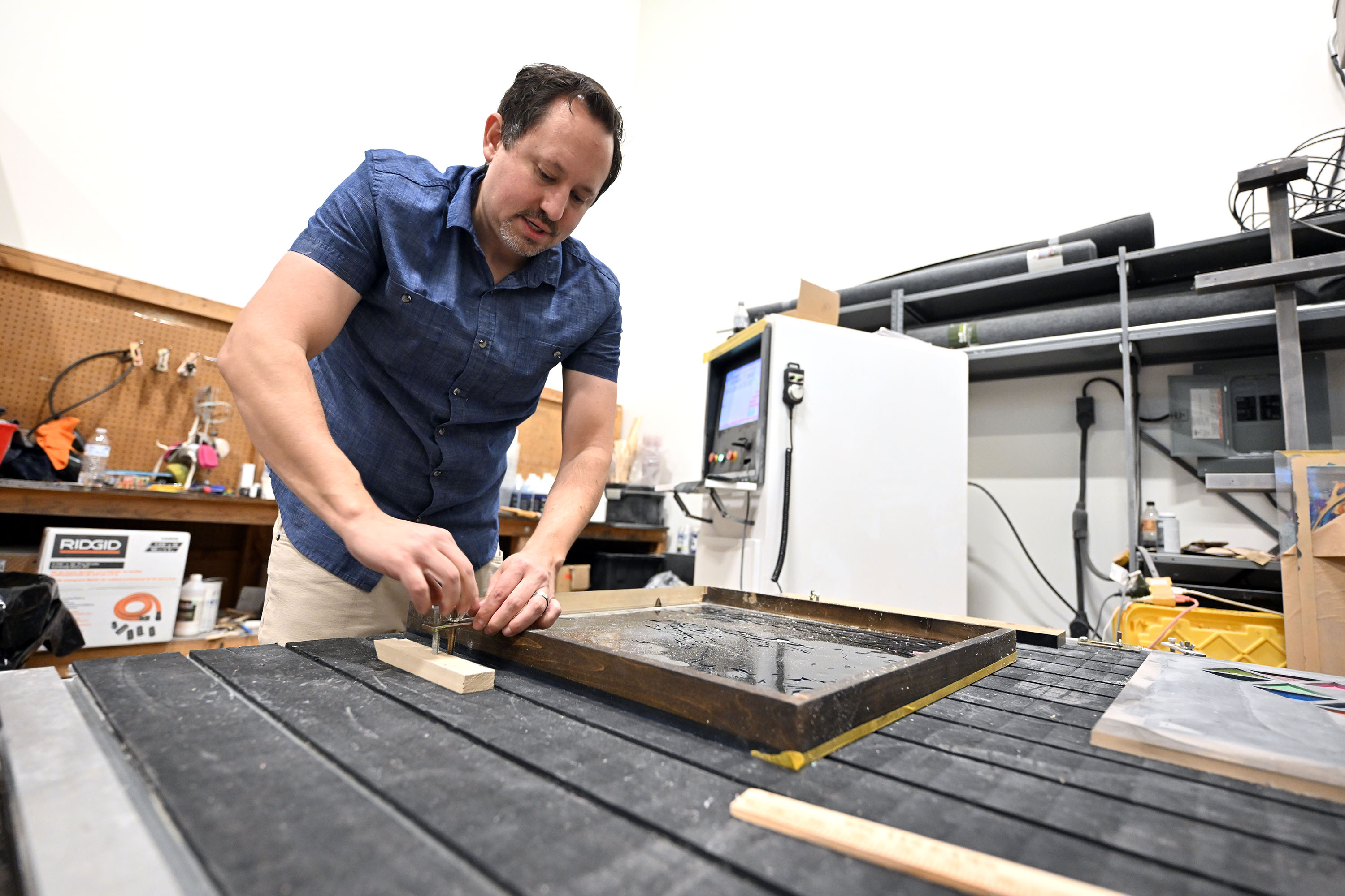 Bluffdale artist Steve Bohls, of Veiled Resin, tightens a clamp on his CNC machine at his shop on Feb. 7.