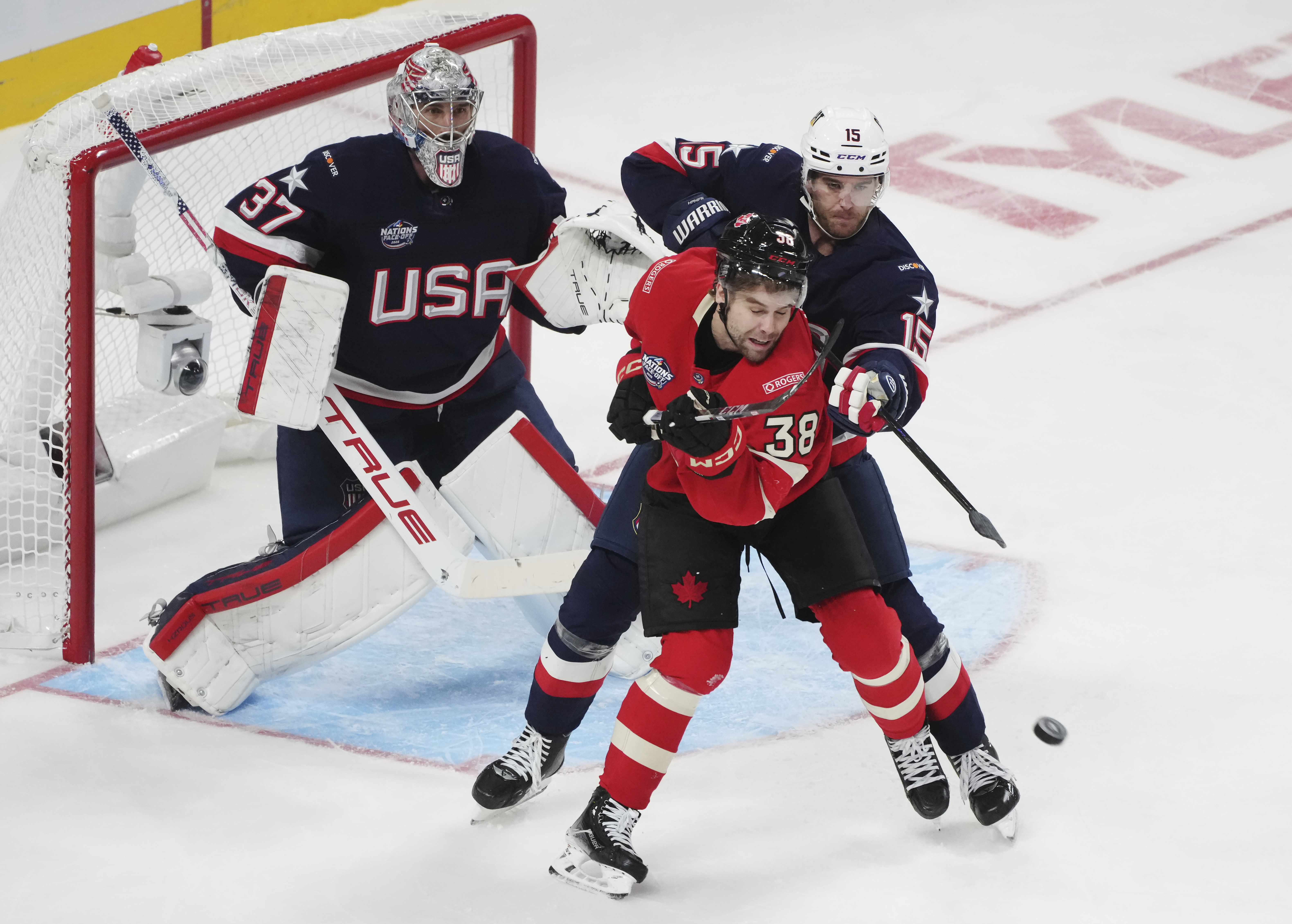 Canada's Brandon Hagel (38) and United States' Noah Hanifin (15) battle in front of goaltender Connor Hellebuyck (37) during third period of 4 Nations Face-Off hockey game in Montreal on Saturday, Feb. 15, 2025. 