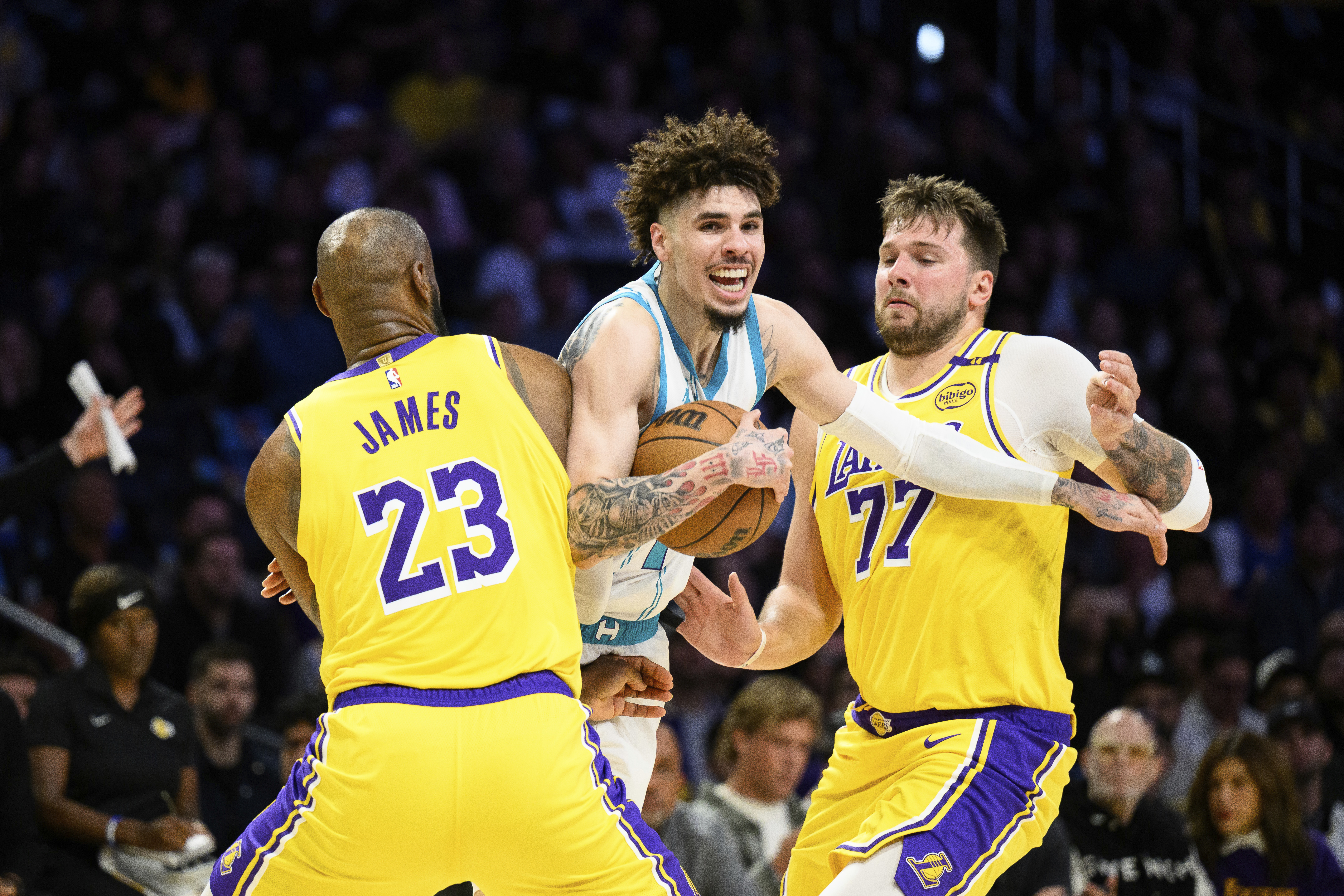 Charlotte Hornets guard LaMelo Ball, center, is contested by Los Angeles Lakers forward LeBron James (23) and Los Angeles Lakers guard Luka Doncic (77) during the first half of an NBA basketball game Wednesday, Feb. 19, 2025, in Los Angeles. 