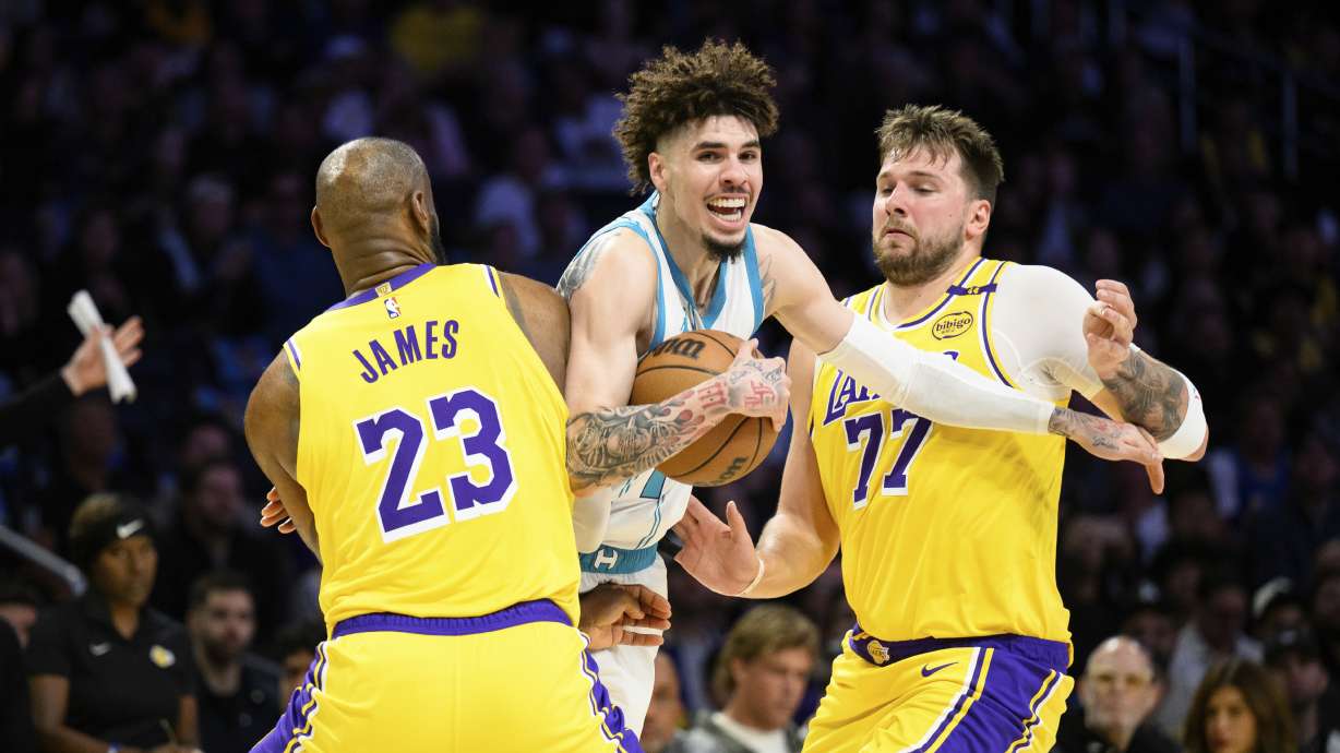 Charlotte Hornets guard LaMelo Ball, center, is contested by Los Angeles Lakers forward LeBron James (23) and Los Angeles Lakers guard Luka Doncic (77) during the first half of an NBA basketball game Wednesday, Feb. 19, 2025, in Los Angeles.