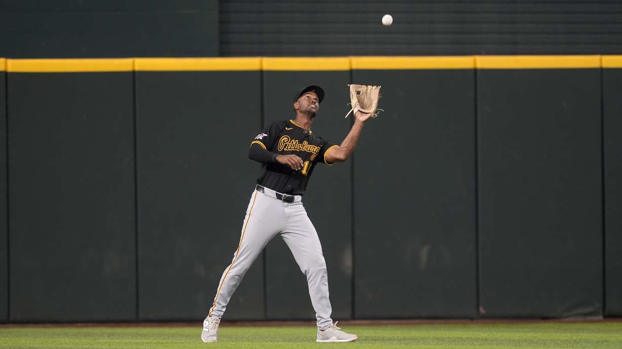 FILE - Pittsburgh Pirates center fielder Michael A. Taylor reaches up to catch a fly out by the Texas Rangers in a baseball game, Aug. 21, 2024, in Arlington, Texas.