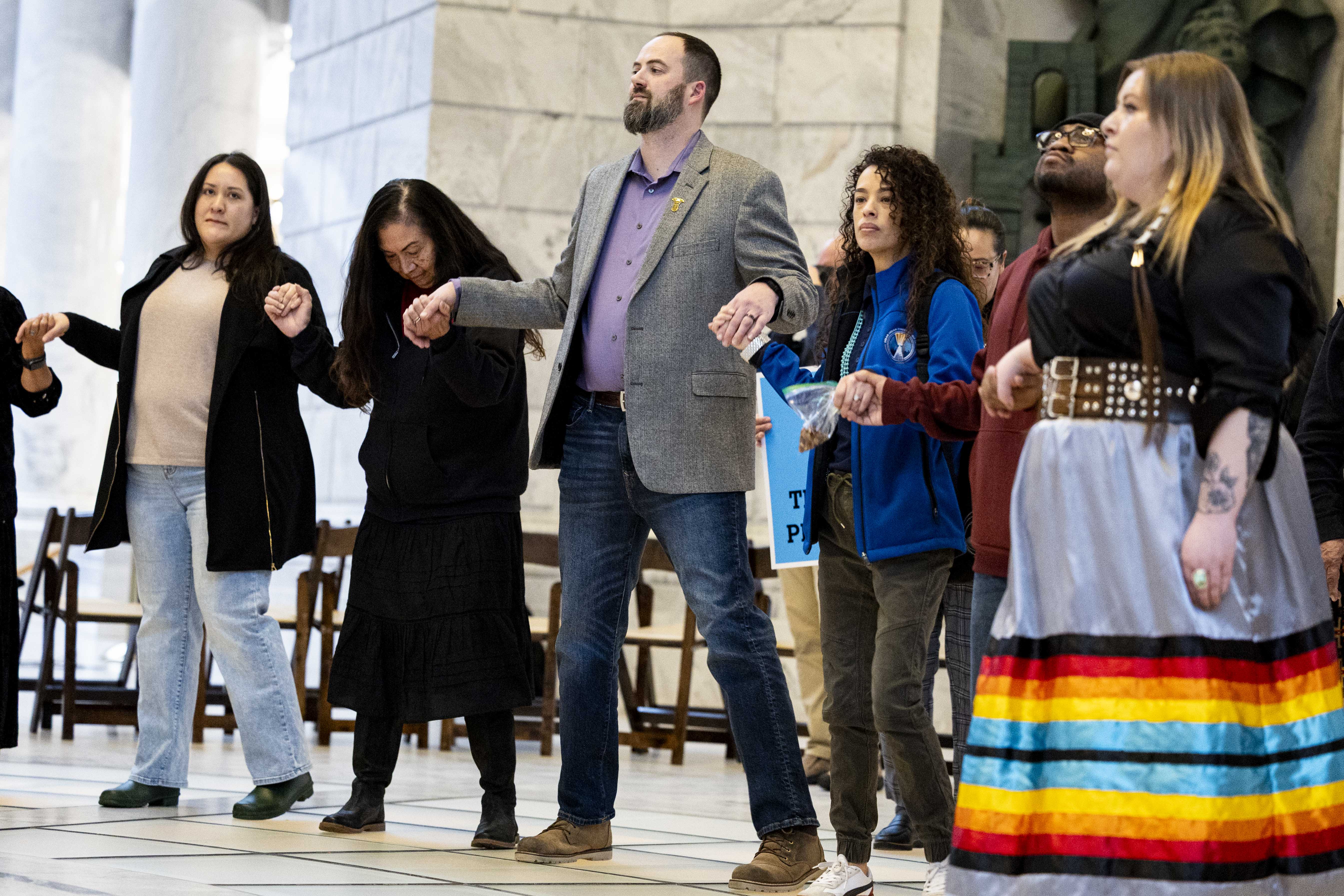 Matt Poss, third from left, interim executive director and director of finance operations of the Urban Indian Center of Salt Lake, walks in a circle hand-in-hand with other attendees during a rally supporting the Indian Family Preservation Act, also known as HB30, held in the rotunda of the Capitol in Salt Lake City on Thursday.