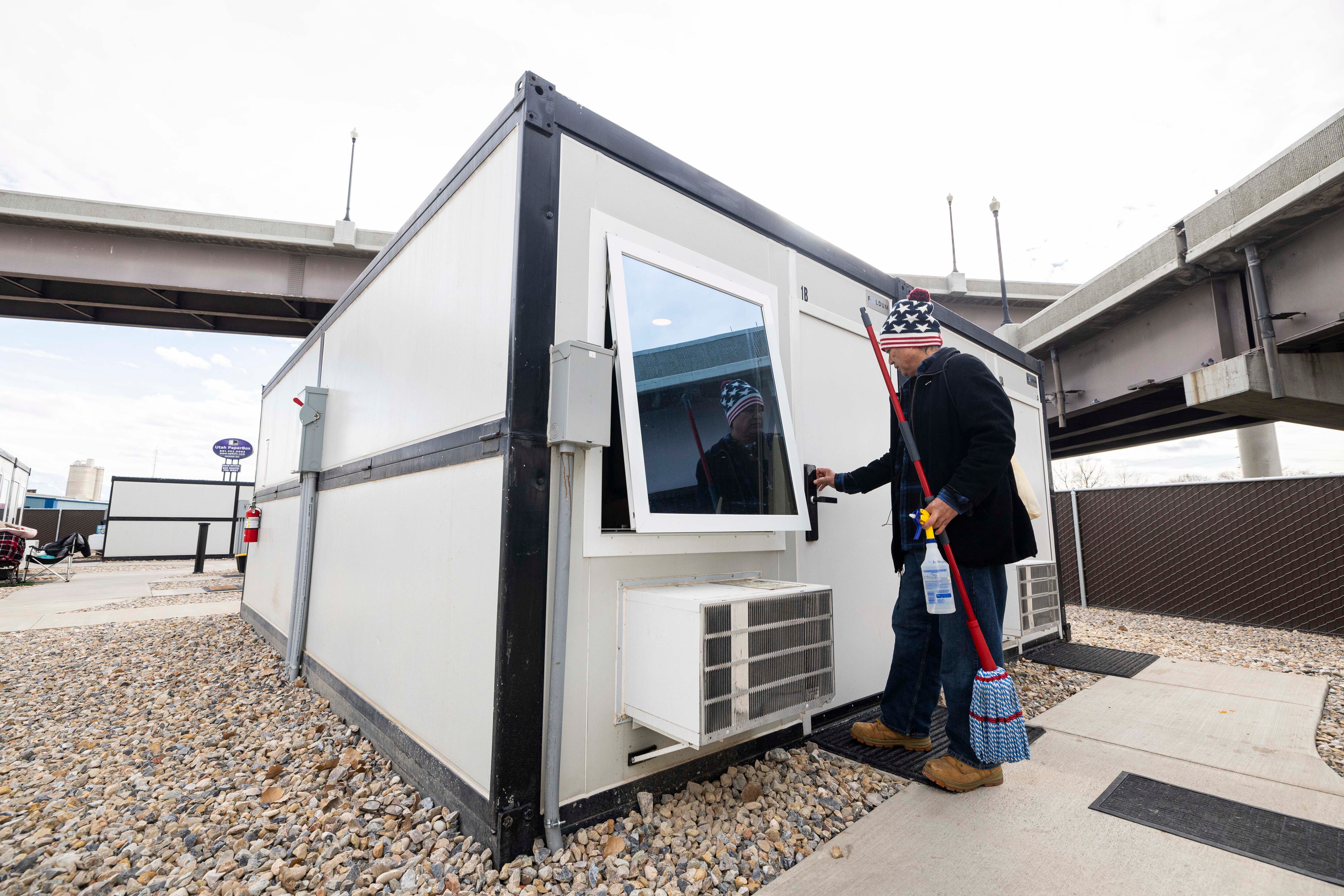 Dixie Nennis enters his microshelter unit with cleaning items before cleaning it at a microshelter community operated by Switchpoint in Salt Lake City on Feb. 6.