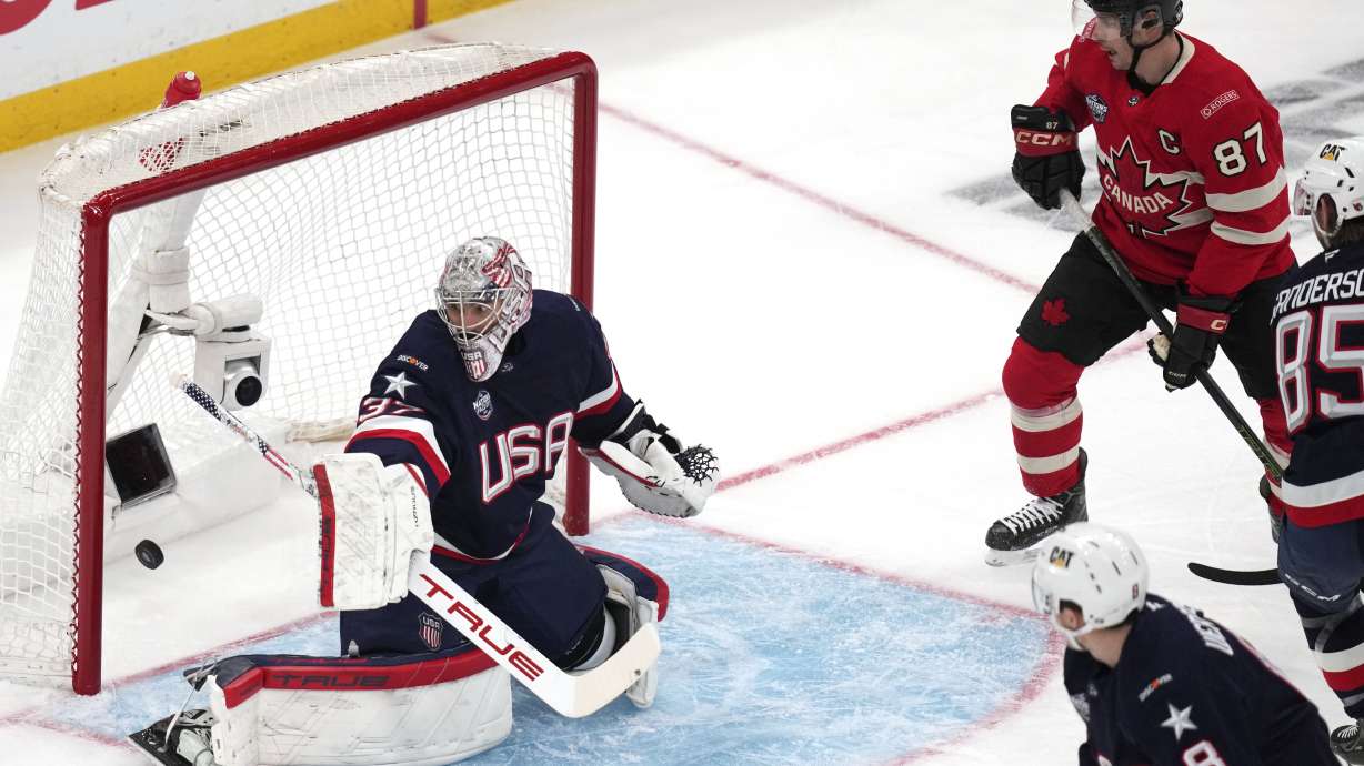 United States goalie Connor Hellebuyck, left, gives up a goal to Canada's Nathan MacKinnon, as Canada's Sidney Crosby (87) looks on, during the first period of the 4 Nations Face-Off championship hockey game, Thursday, Feb. 20, 2025, in Boston.