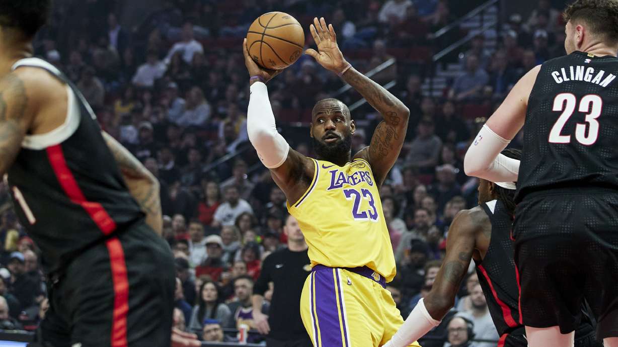 Los Angeles Lakers forward LeBron James, center, looks to pass the ball between Portland Trail Blazers center Donovan Clingan, right, and guard Anfernee Simons during the first half of an NBA basketball game in Portland, Ore., Thursday, Feb. 20, 2025.