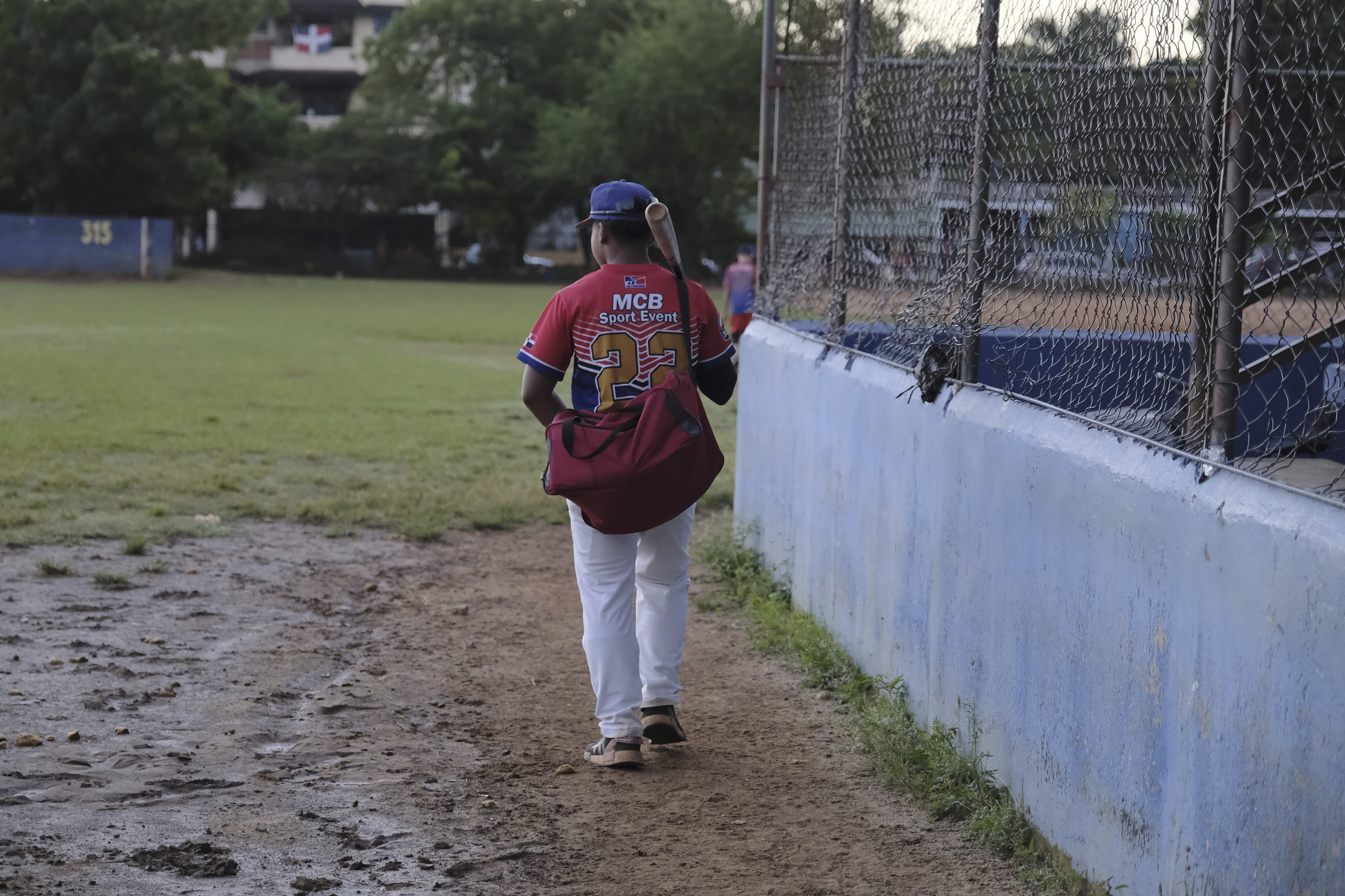 A teenage baseball player, wearing an MCB Sport Event jersey, arrives for practice at the Trinitarios ballpark in Santo Domingo, Dominican Republic, Wednesday, Feb. 5, 2025.