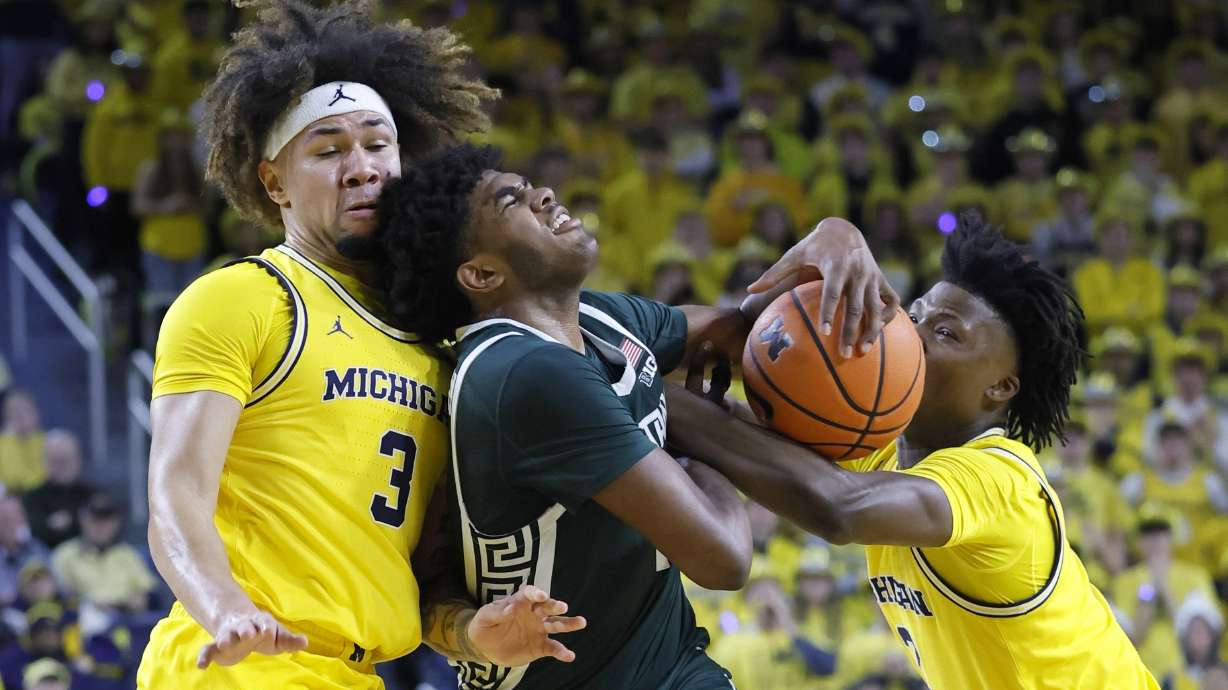 Michigan State guard Jase Richardson, center, is fouled by Michigan guard L.J. Cason, right, while also going to the basket against guard Tre Donaldson (3) during the first half of an NCAA college basketball game Friday, Feb. 21, 2025, in Ann Arbor, Mich.