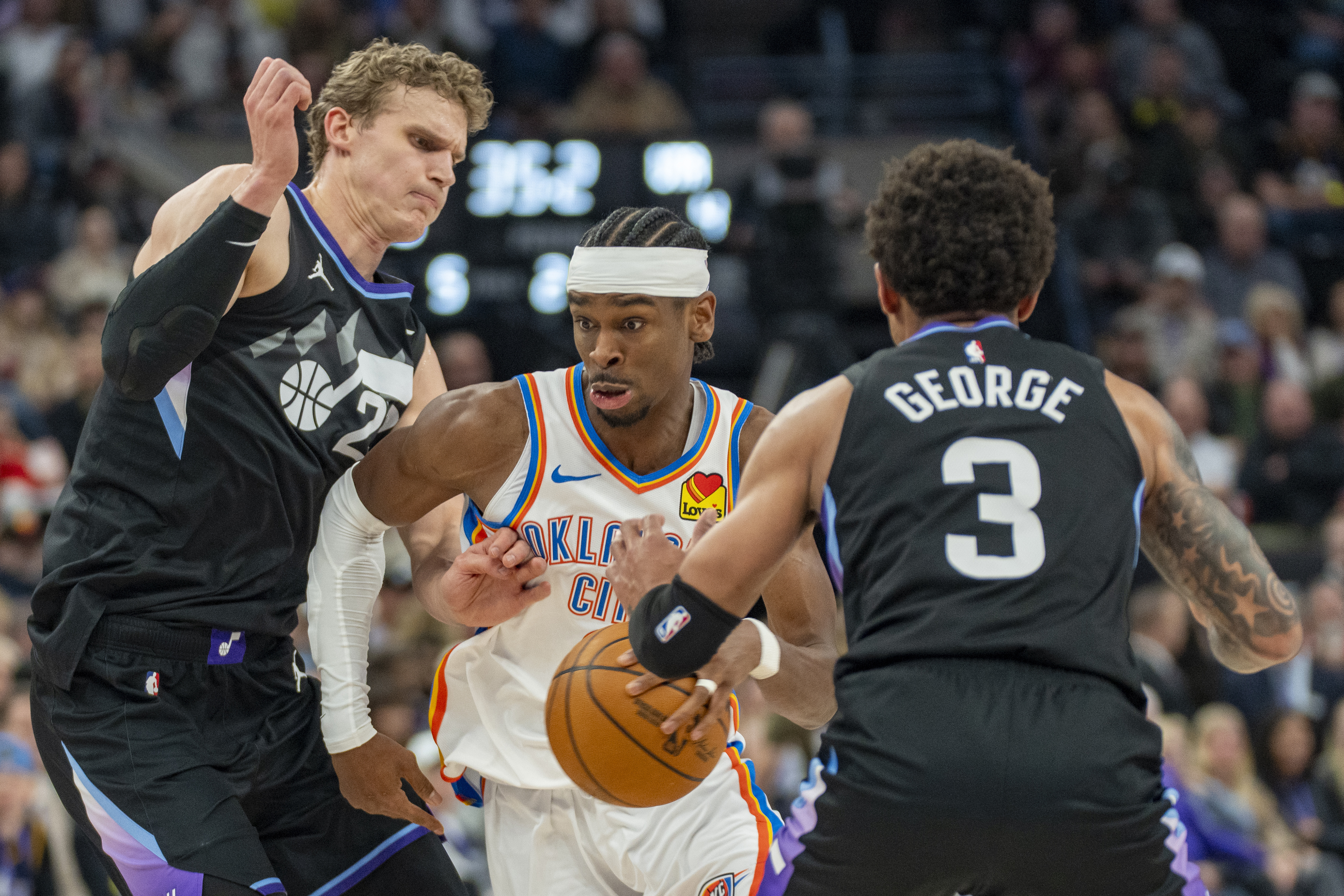 Oklahoma City Thunder guard Shai Gilgeous-Alexander, middle, dribbles between Utah Jazz forward Lauri Markkanen, left, and Utah Jazz guard Keyonte George (3), during the first half of an NBA basketball game Friday, Feb. 21, 2025, in Salt Lake City. 