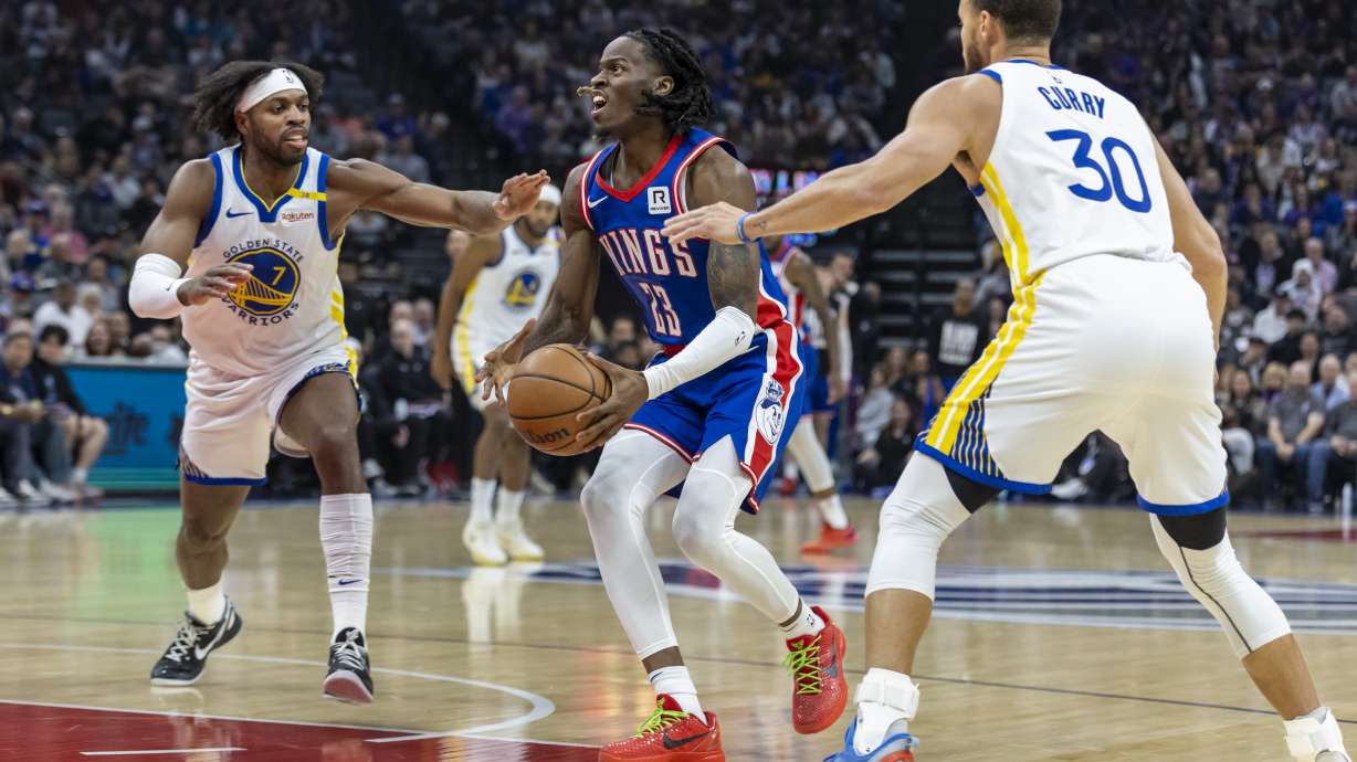 Sacramento Kings guard Keon Ellis (23) attempts a shot with Golden State Warriors guard Buddy Hield (7) and Golden State Warriors guard Stephen Curry (30) on defense during the first half of an NBA basketball game Friday, Feb. 21, 2025, in Sacramento, Calif.