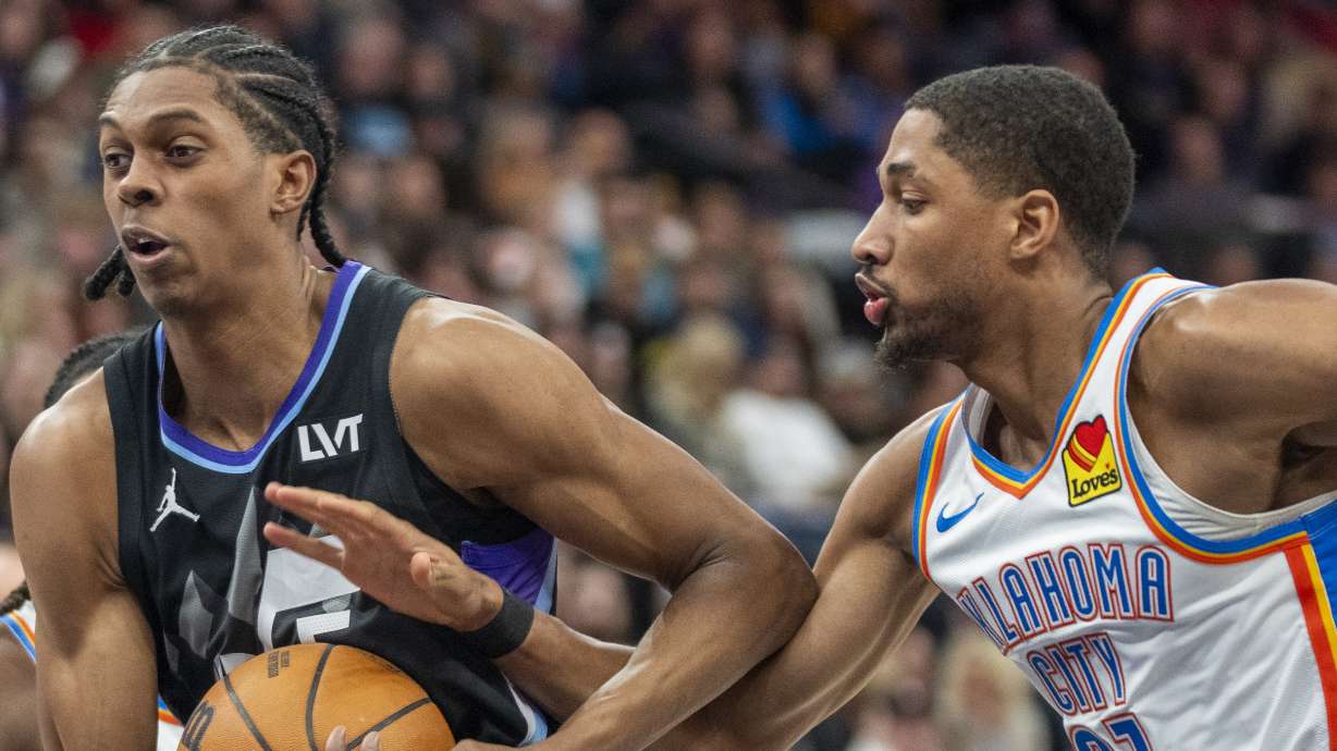 Utah Jazz forward Cody Williams, left, goes to the hoop, as Oklahoma City Thunder guard Aaron Wiggins (21) defends during the first half of an NBA basketball game Friday, Feb. 21, 2025, in Salt Lake City.