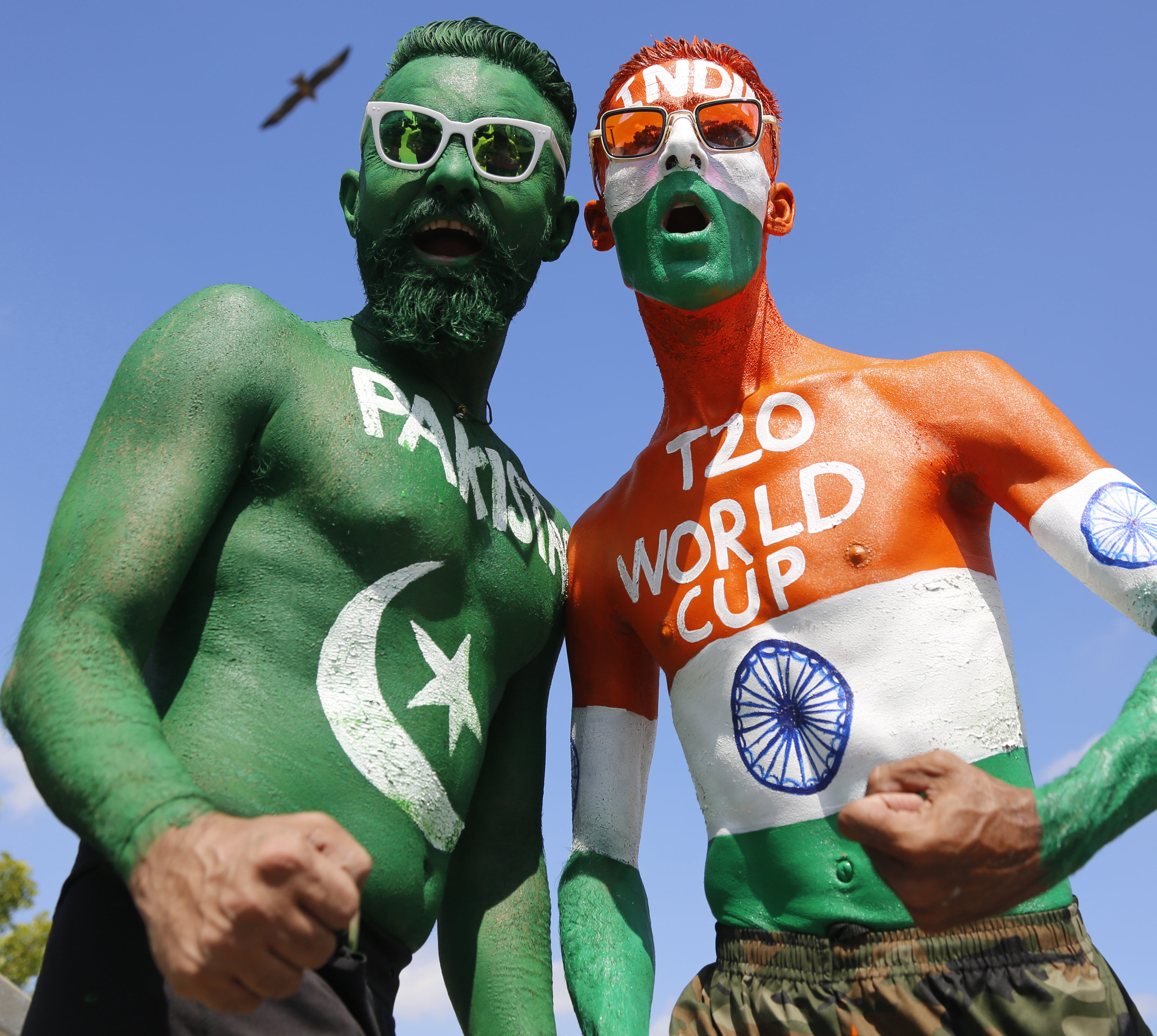 Indian cricket fans, their bodies painted in the colors of the national flags of India, right and Pakistan,left, pose for photograph in Ahmedabad, India, Oct. 23, 2021.