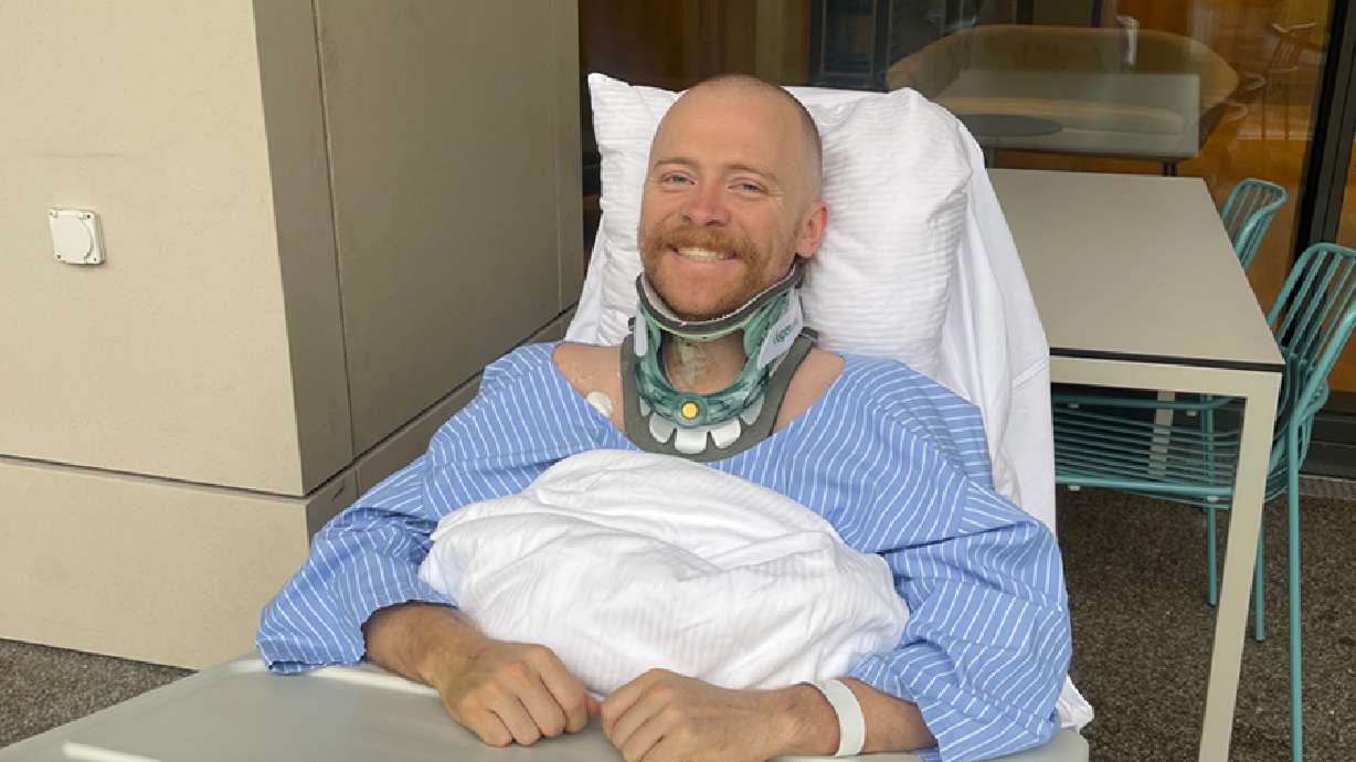 Justin Holman smiles from his hospital bed in Bern, Switzerland. Holman remains stranded after a flight to get him home to Colorado was canceled.