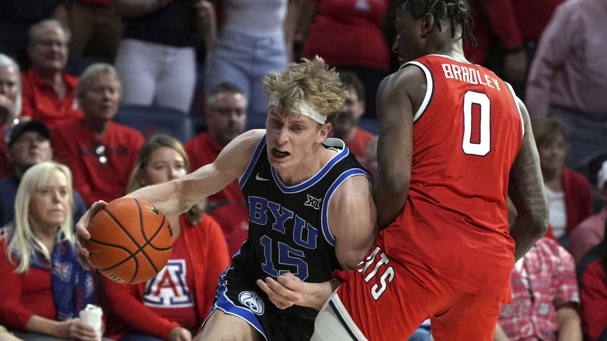 BYU forward Richie Saunders (15) drives against Arizona guard Jaden Bradley (0) during the first half of an NCAA college basketball game, Saturday, Feb. 22, 2025, in Tucson, Ariz.