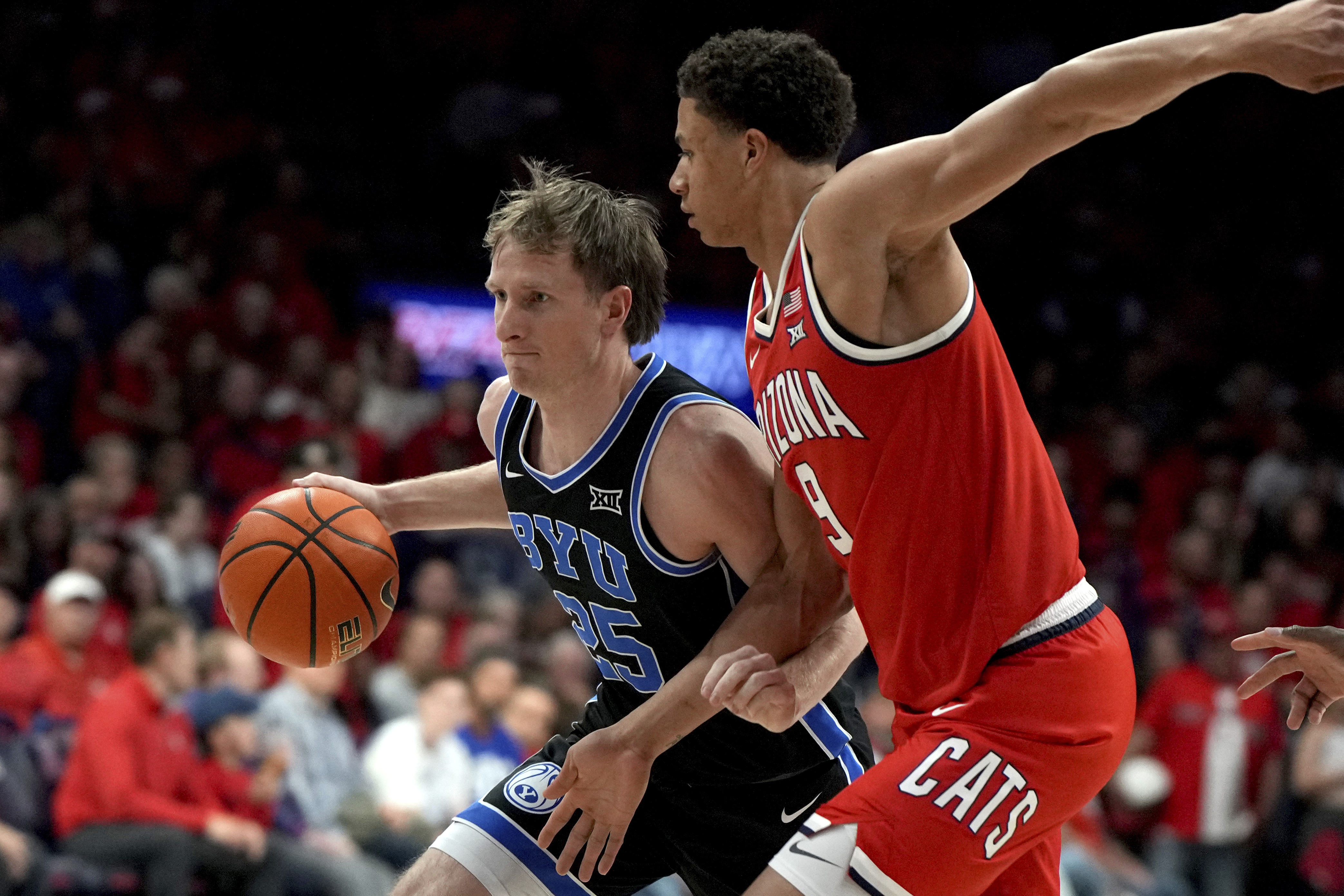 BYU guard Dawson Baker (25) moves against Arizona forward Carter Bryant, right, during the first half of an NCAA college basketball game, Saturday, Feb. 22, 2025, in Tucson, Ariz.