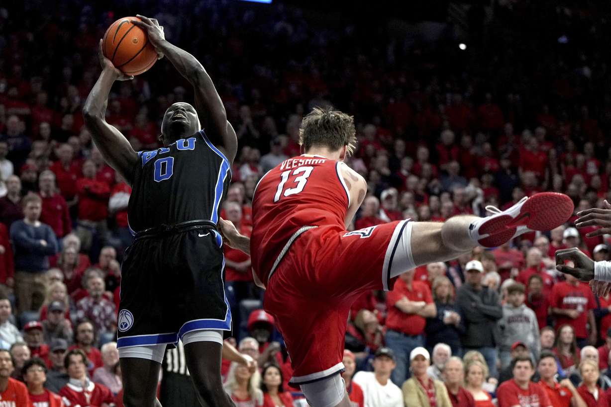 BYU forward Mawot Mag is fouled by Arizona forward Henri Veesaar (13) during the first half of an NCAA college basketball game, Saturday, Feb. 22, 2025, in Tucson, Ariz.