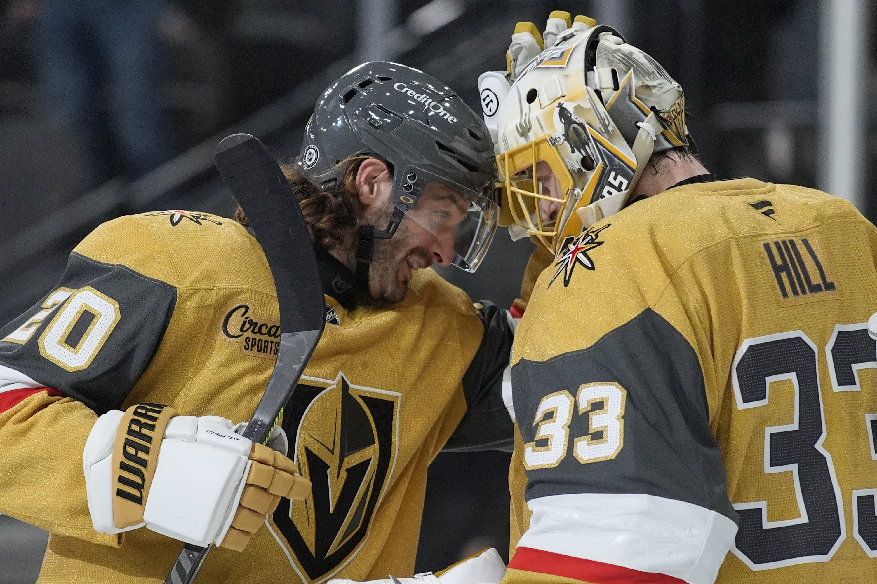 Vegas Golden Knights left wing Brandon Saad (20) and goaltender Adin Hill (33) celebrate after their team defeated the Vancouver Canucks in an NHL hockey game Saturday, Feb. 22, 2025, in Las Vegas. 