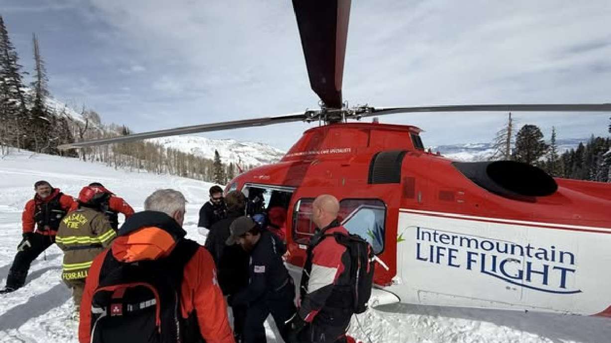 A Life Flight helicopter aids in the rescue of two snowmobilers who got caught in an avalanche in the Snake Creek of Wasatch County on Saturday.