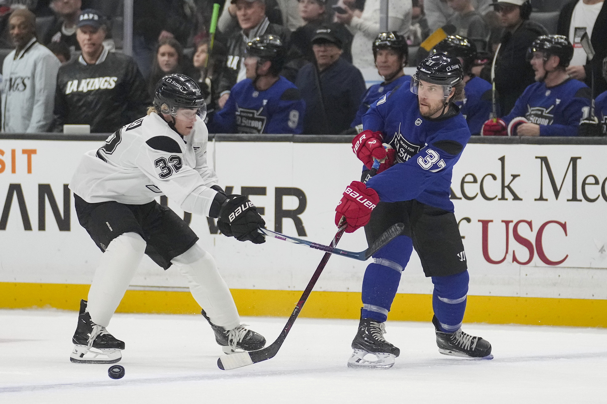 Team Blue player actor Taylor Kitsch passes the puck against Team White player actor and singer Ross Lynch during the Skate for LA Strong celebrity hockey game, Sunday, Feb. 23, 2025, in Los Angeles.