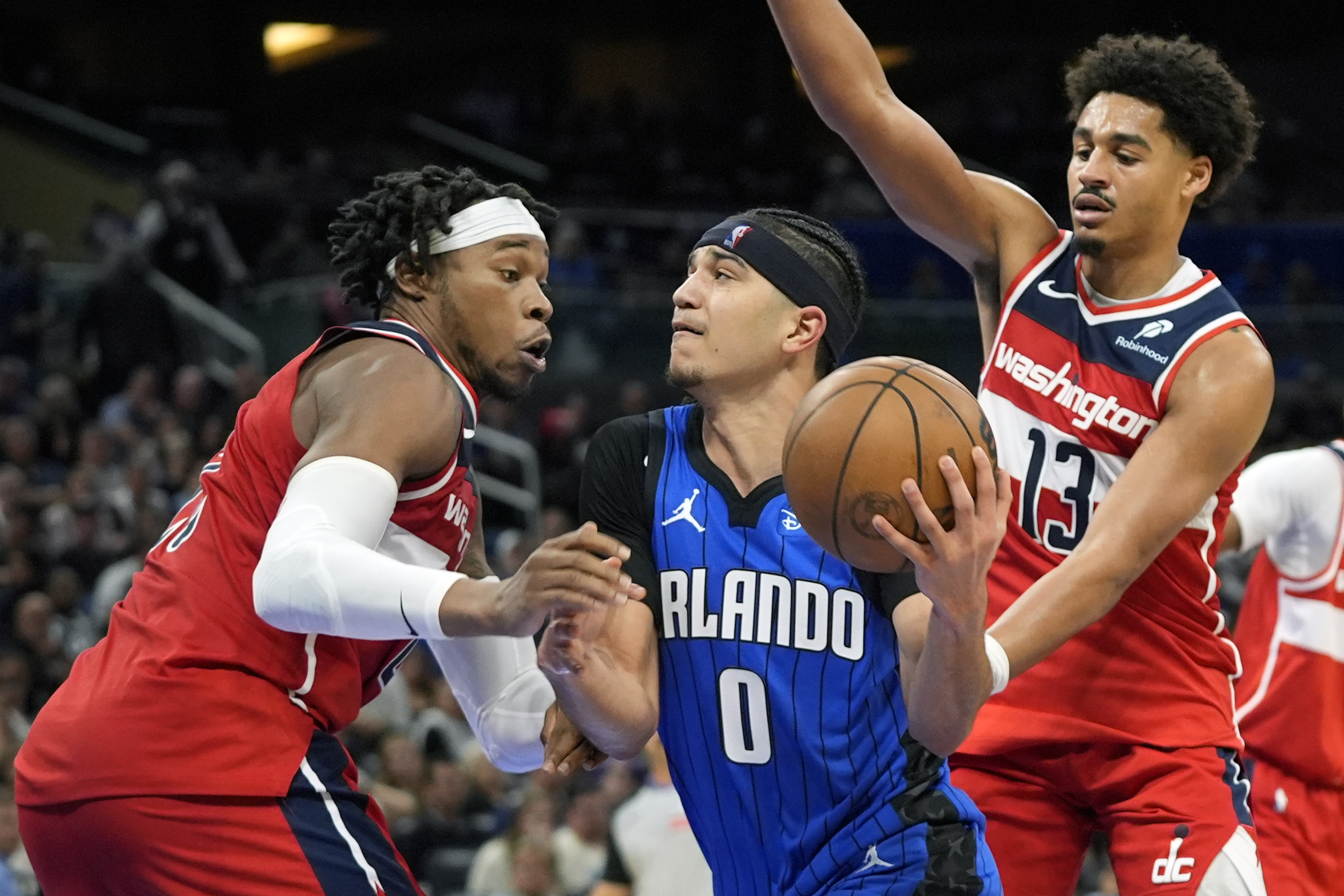 Orlando Magic guard Anthony Black (0) drives to the basket between Washington Wizards forward Richaun Holmes, left, and guard Jordan Poole (13) during the second half of an NBA basketball game, Sunday, Feb. 23, 2025, in Orlando, Fla. 
