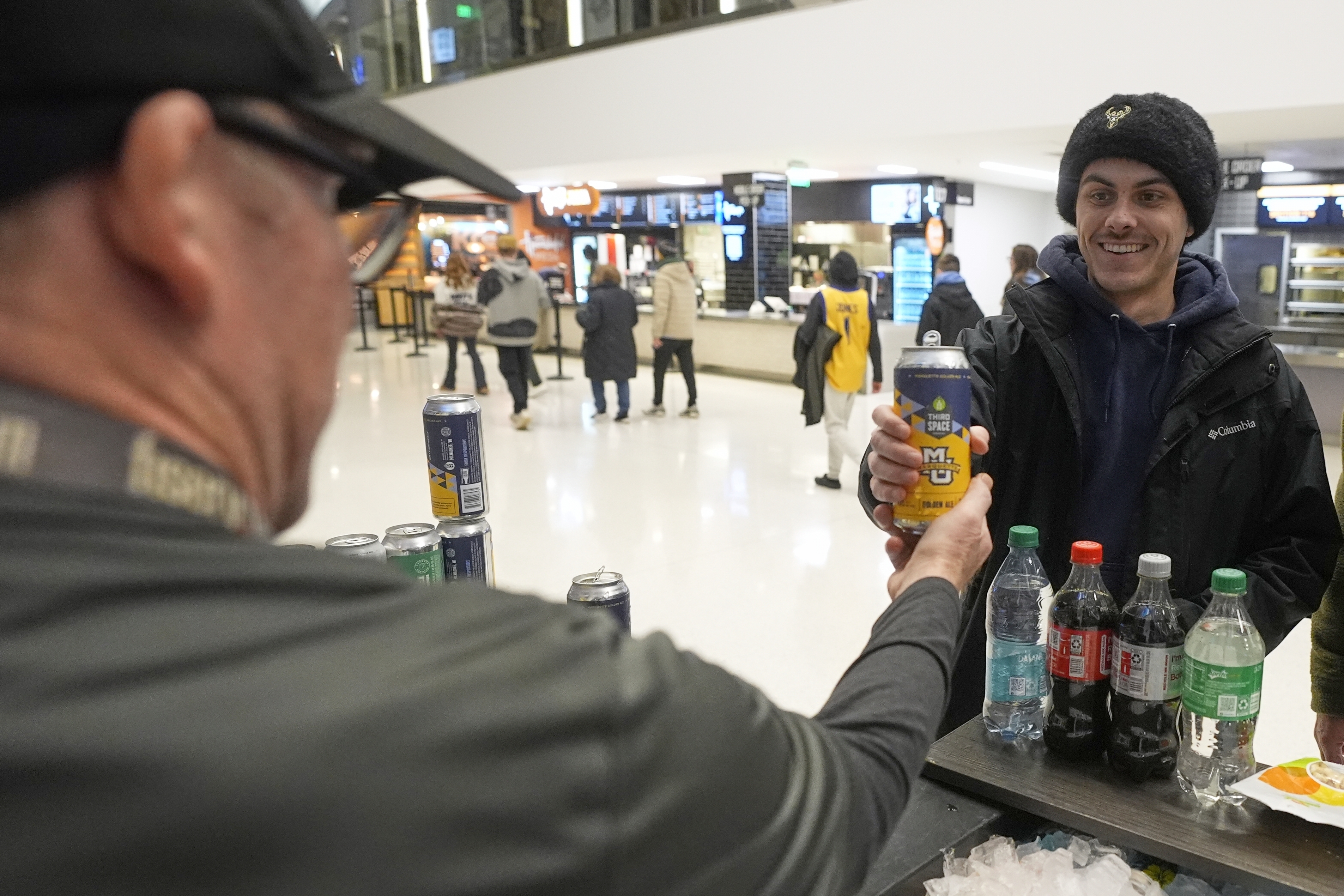 Jimmy Gross serves Jonathon Holdway some Third Space Marquette beer before an NCAA college basketball game Tuesday, Feb. 11, 2025, in Milwaukee. 