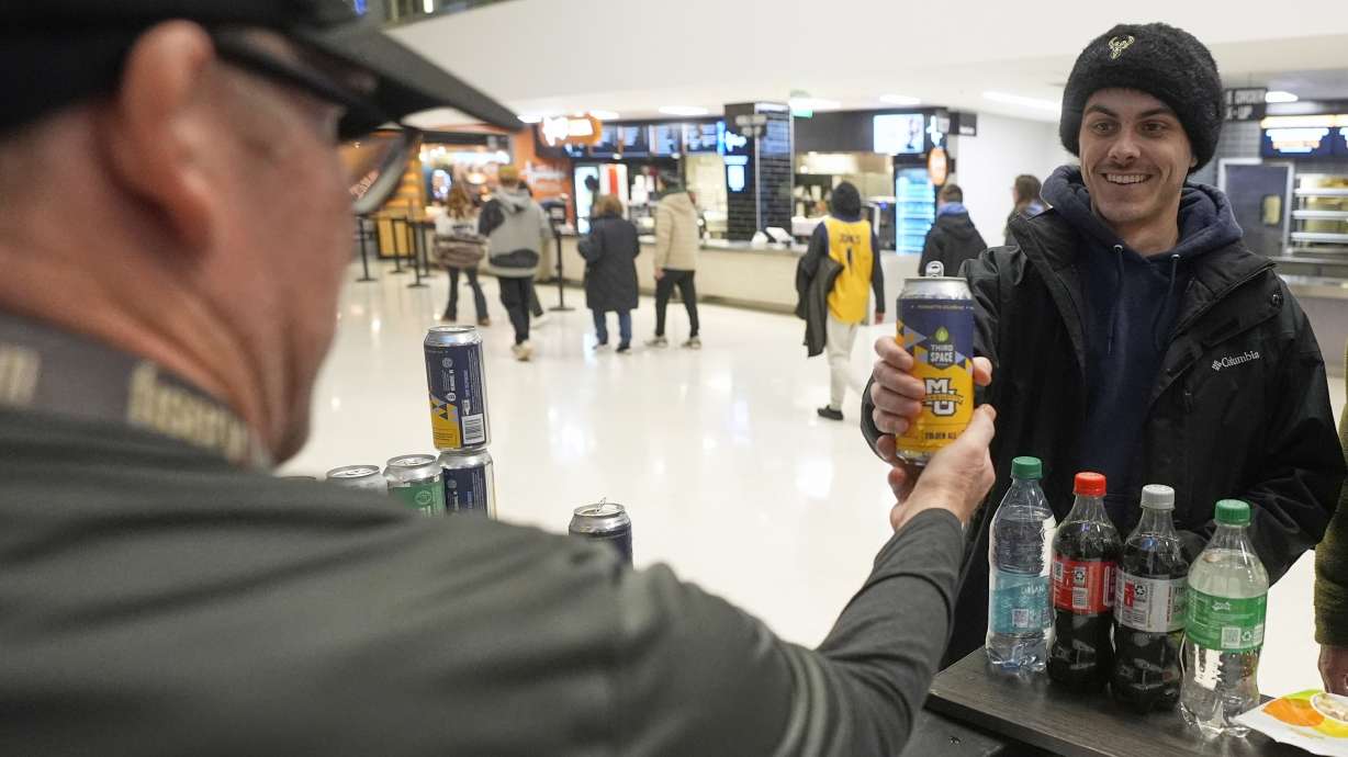 Jimmy Gross serves Jonathon Holdway some Third Space Marquette beer before an NCAA college basketball game Tuesday, Feb. 11, 2025, in Milwaukee.