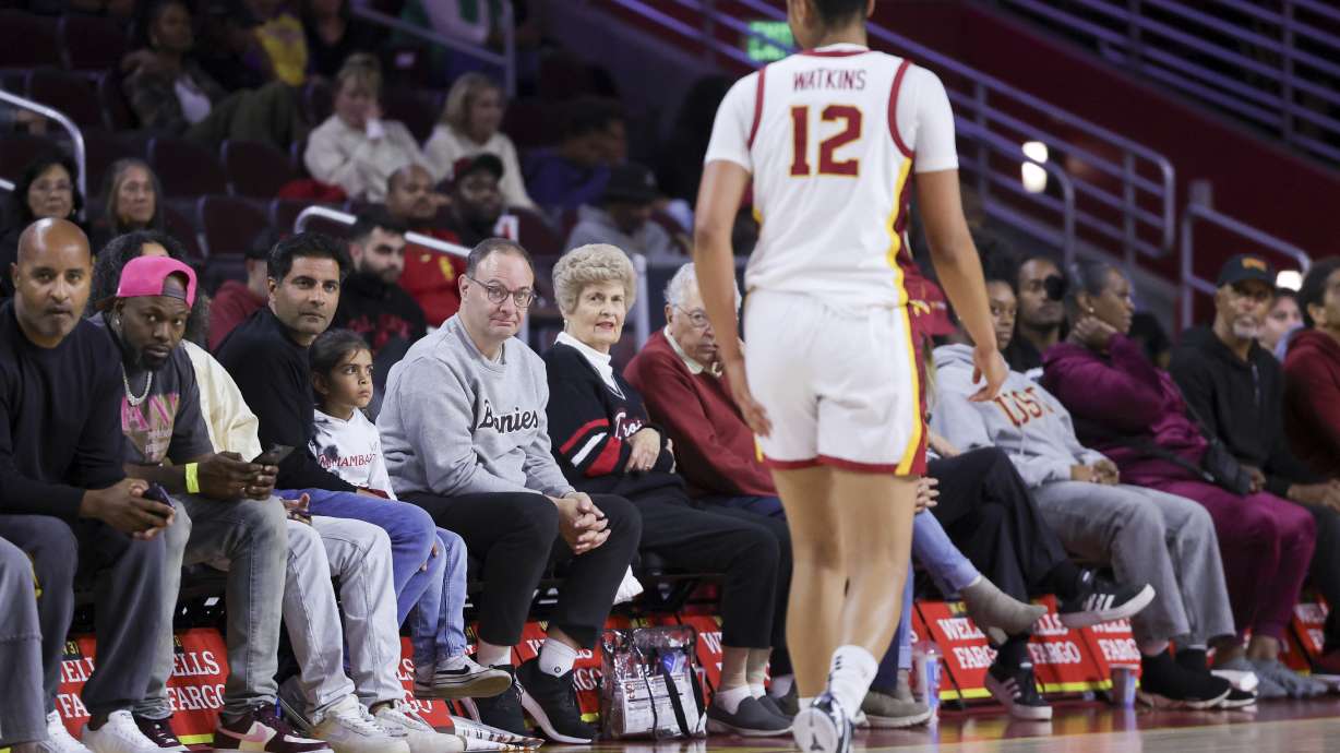 FILE - Former NBA reporter and current St. Bonaventure men's basketball general manager Adrian Wojnarowski, center left, watches as Southern California guard JuJu Watkins walks past during the second half of an NCAA women's basketball game, Nov. 12, 2024, in Los Angeles.