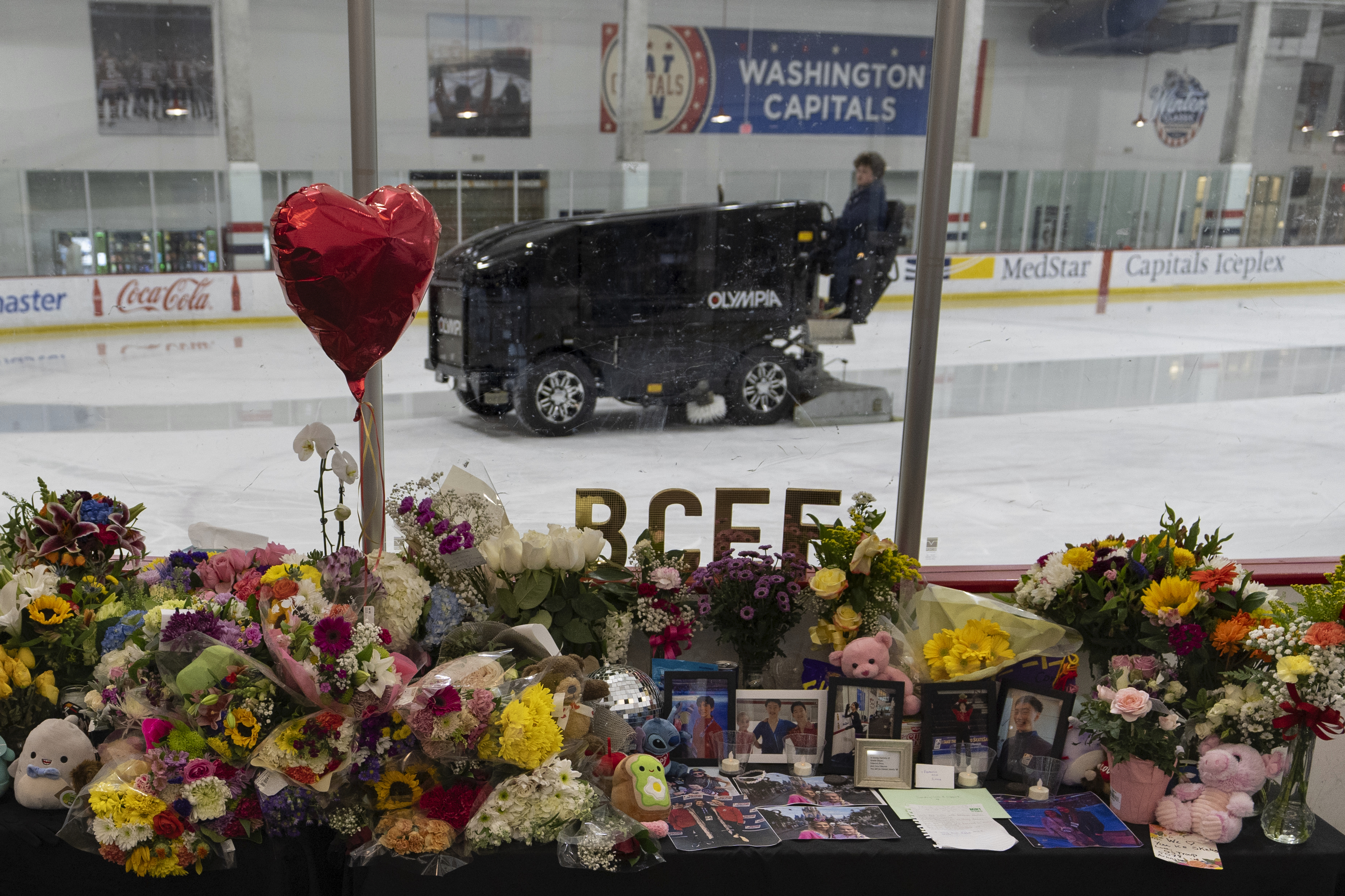 An ice resurfacer prepares the ice as a memorial is seen along the boards at MedStar Capitals Iceplex Sunday, Feb. 2, 2025, in Arlington, Va., for the figure skaters who were among the 67 victims of a mid-air collision between an Army helicopter and an American Airlines flight from Kansas. 