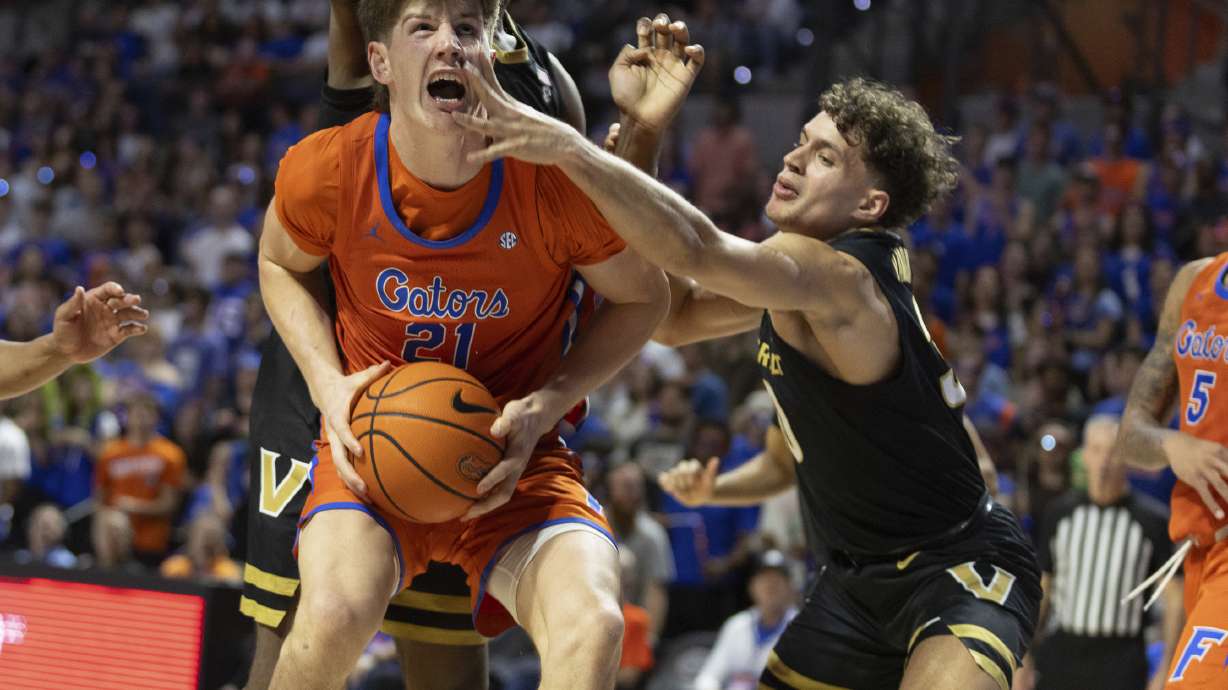 Florida forward Alex Condon (21) rebounds pressured by Vanderbilt guard Chris Manon, right, during the second half of an NCAA college basketball game Tuesday, Feb. 4, 2025, in Gainesville, Fla.