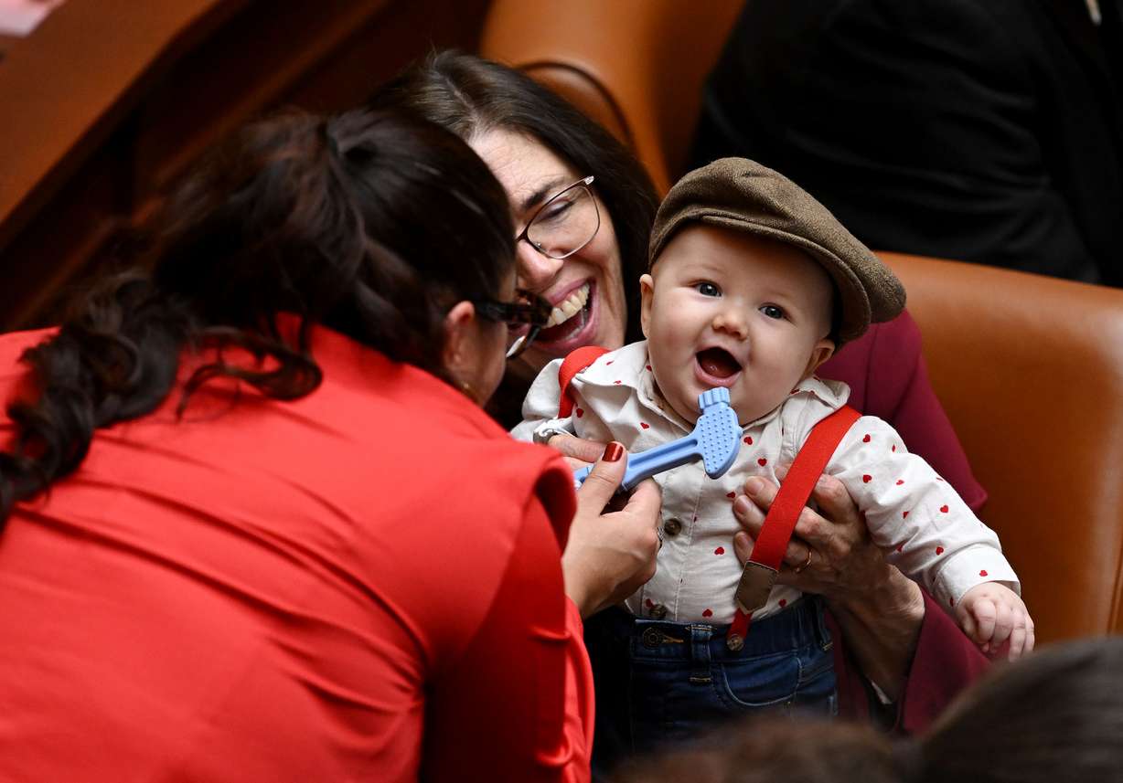 Rep. Gay Lynn Bennion, D-Cottonwood Heights, and Rep. Ashlee Matthews, D-West Jordan, go about their responsibilities in the House of Representatives while carrying baby Joey on Feb. 14. Joey gets passed around from staff to representative, whoever would like to hold him during floor time.
