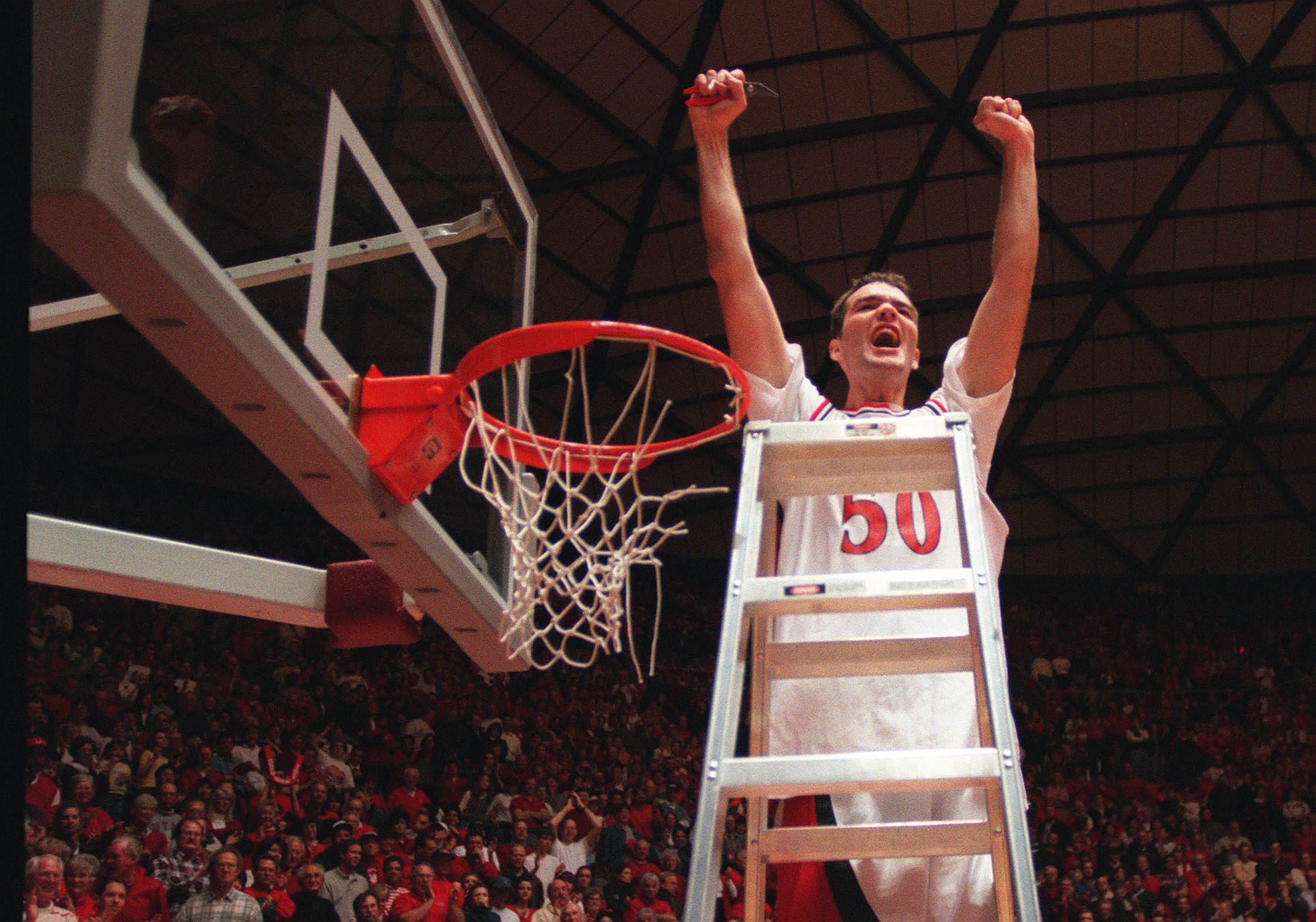 Alex Jensen cuts down net after the Utes won the game with New Mexico.