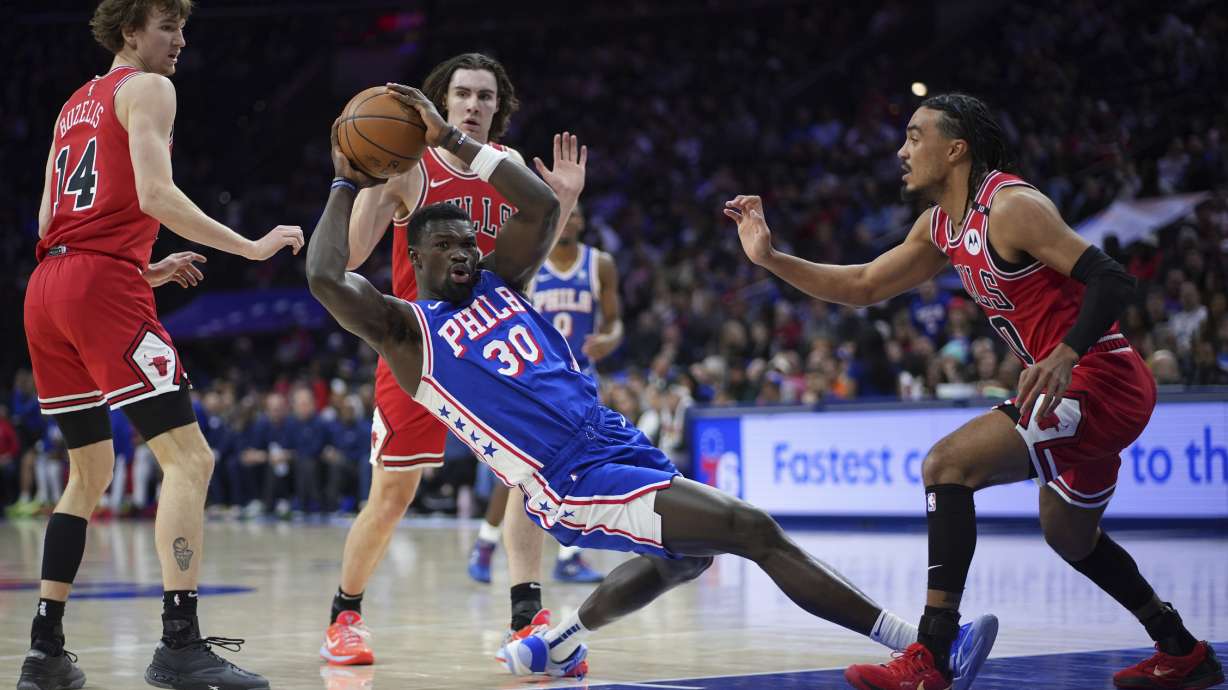 Philadelphia 76ers' Adem Bona, center, falls after being fouled by Chicago Bulls' Josh Giddey, rear, during the first half of an NBA basketball game Monday, Feb. 24, 2025, in Philadelphia.