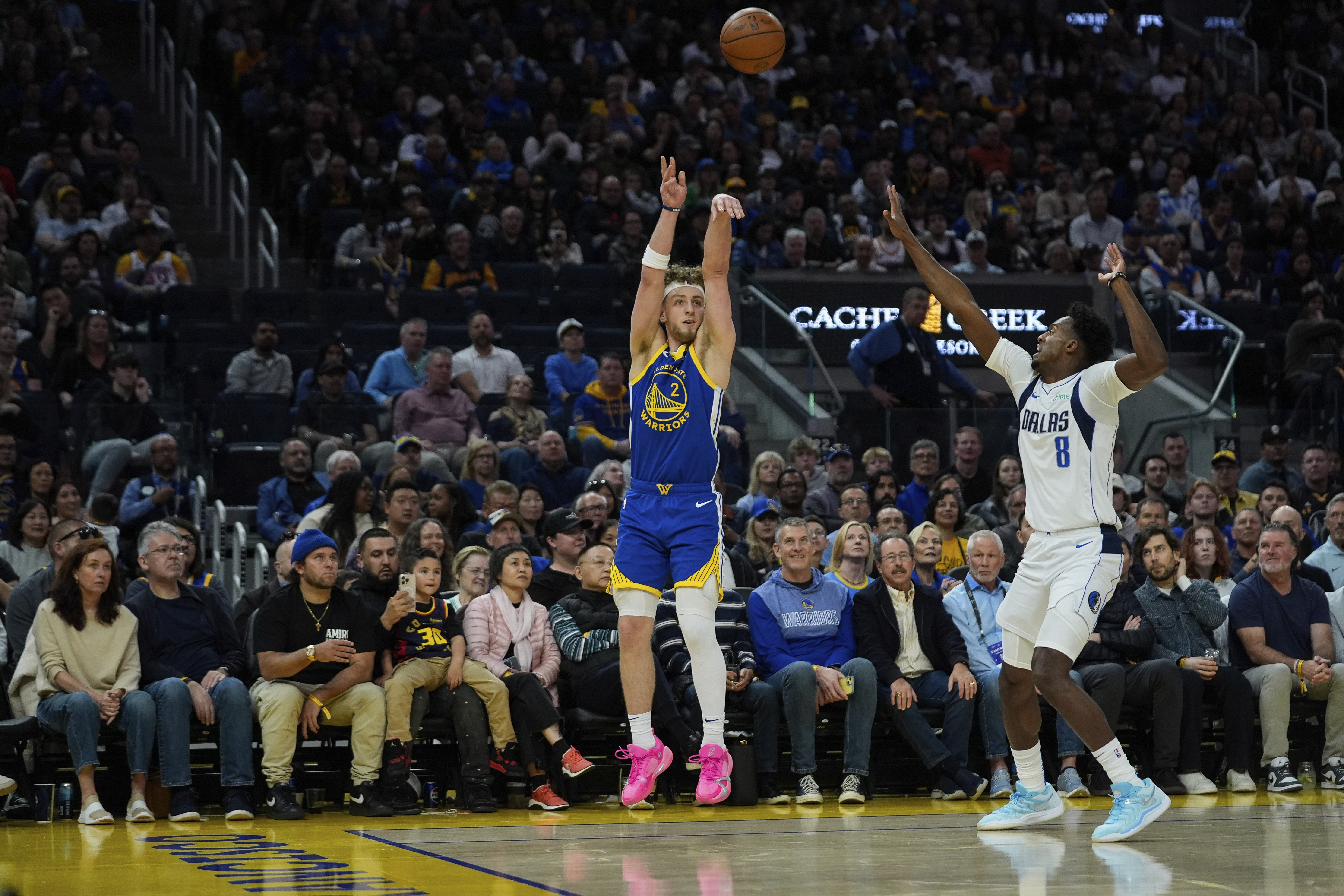 Golden State Warriors guard Brandin Podziemski (2) shoots a 3-point basket next to Dallas Mavericks forward Olivier-Maxence Prosper (8) during the second half of an NBA basketball game Sunday, Feb. 23, 2025, in San Francisco.