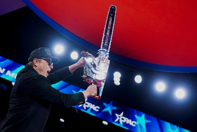 Elon Musk holds up a chainsaw onstage during the Conservative Political Action Conference in National Harbor, Md., Feb. 20. Musk warned that federal employees will be given "a second chance" to respond to his email asking them to justify their jobs or risk termination.