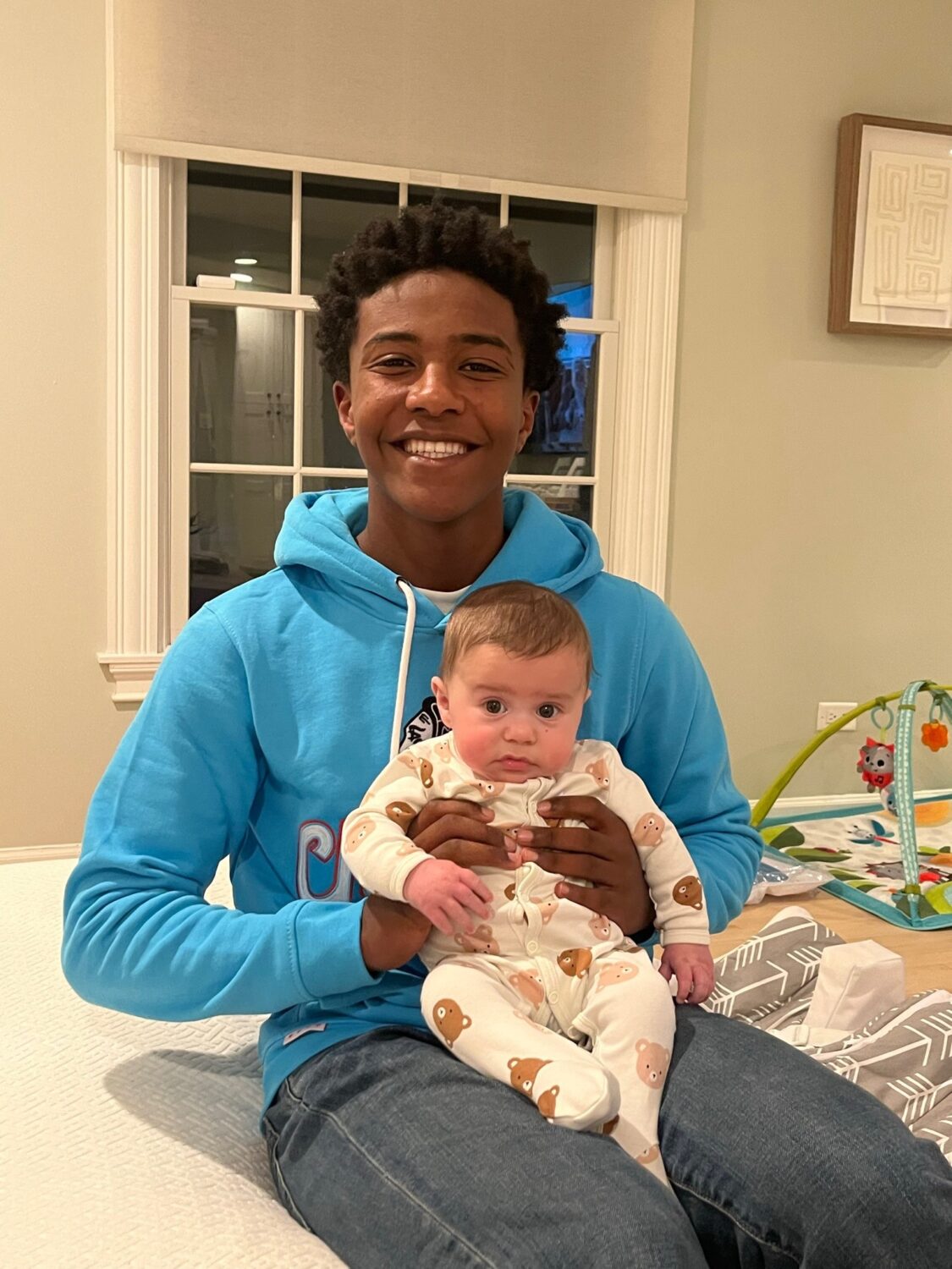 Biruk Silvers holding a baby while smiling at the camera.