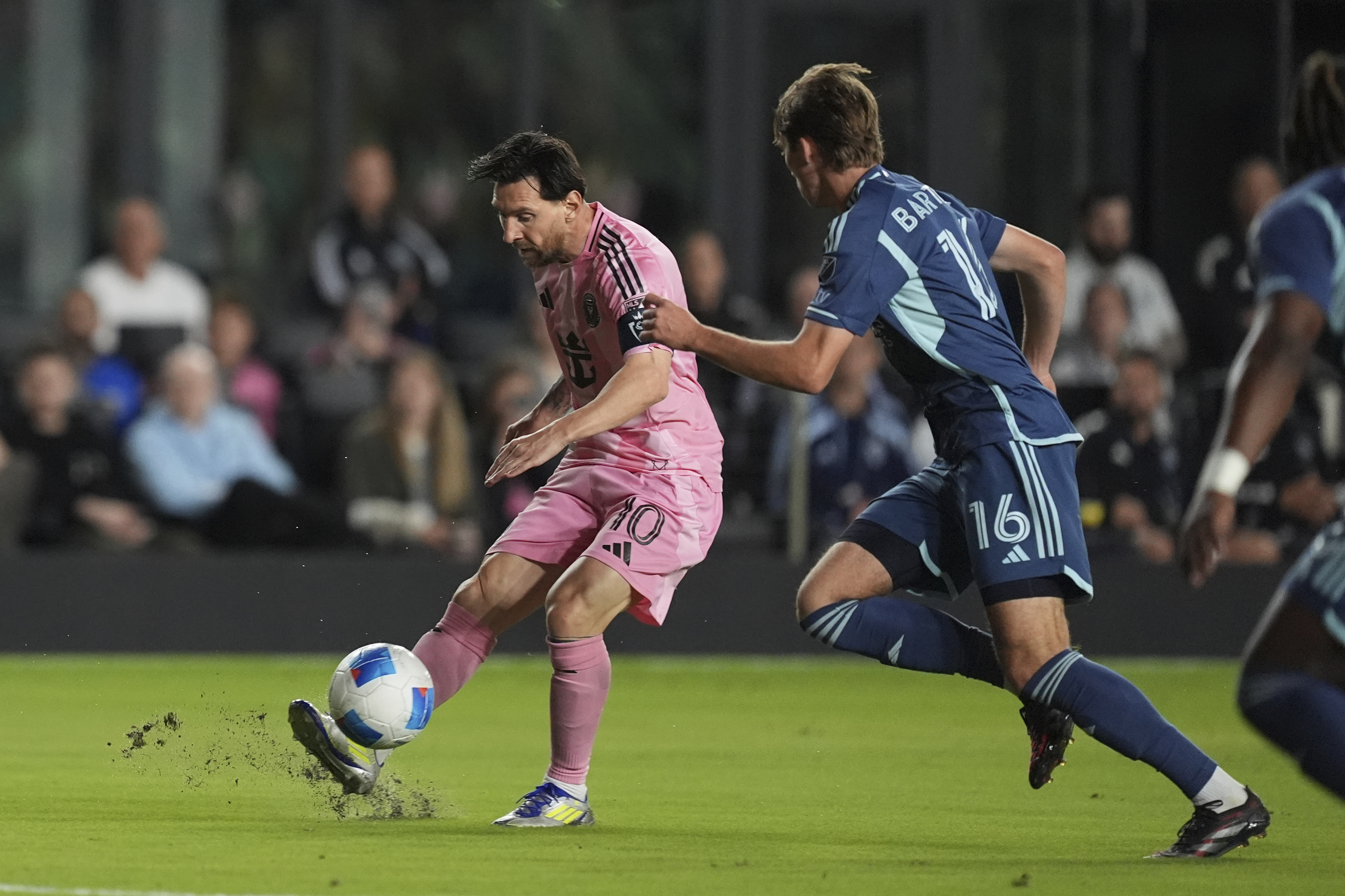 Inter Miami forward Lionel Messi (10) passes, defended by Sporting Kansas City midfielder Jacob Bartlett (16) during the first half of a CONCACAF Champions Cup soccer match, Tuesday, Feb. 25, 2025, in Fort Lauderdale, Fla.