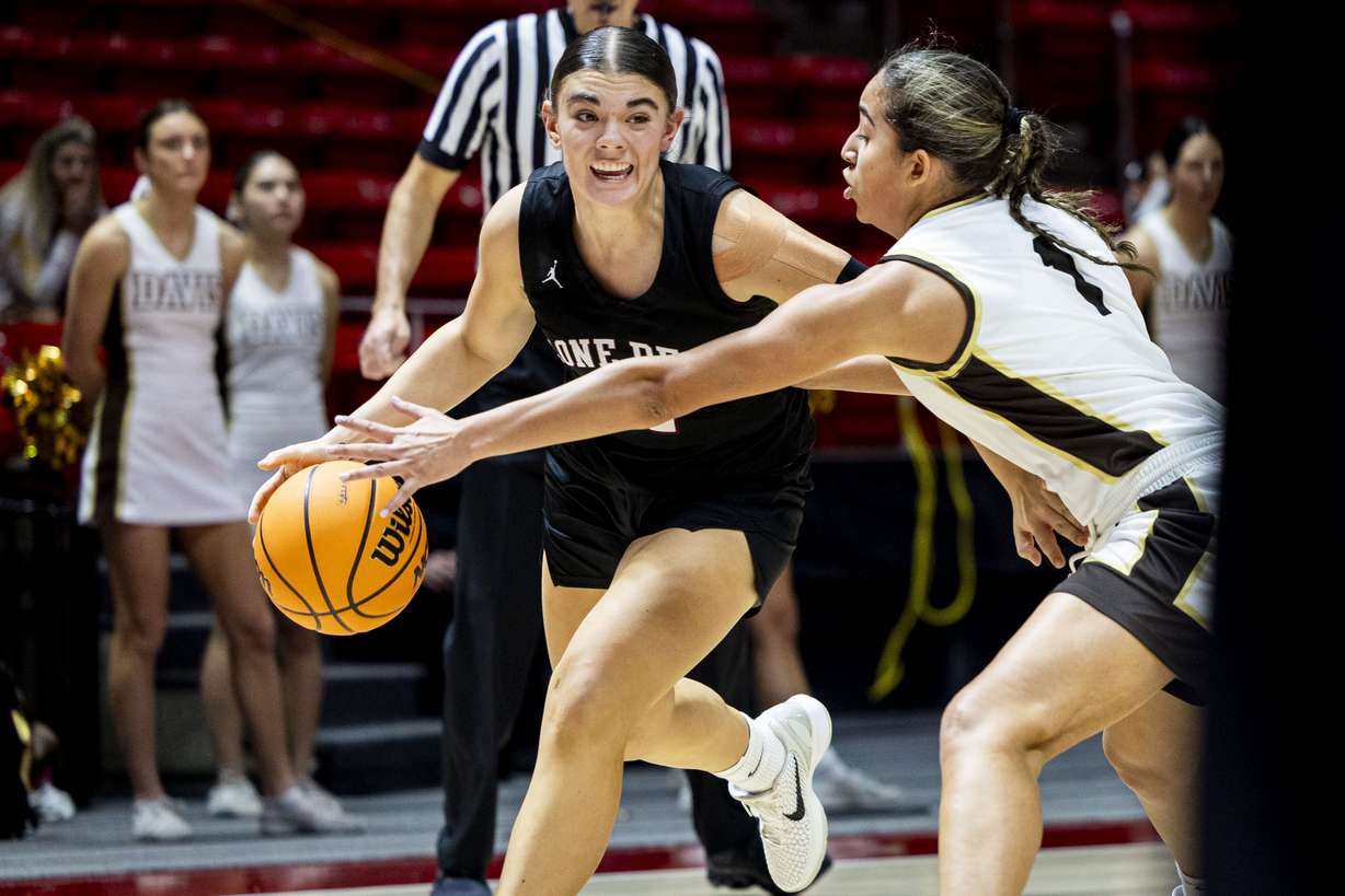 Lone Peak’s Charli Warner (1) drives the ball toward the basket while guarded by Davis guard Sydney Plummer (11) during the 6A girls basketball semifinals held at the Huntsman Center in Salt Lake City on Wednesday, Feb. 26, 2025.
