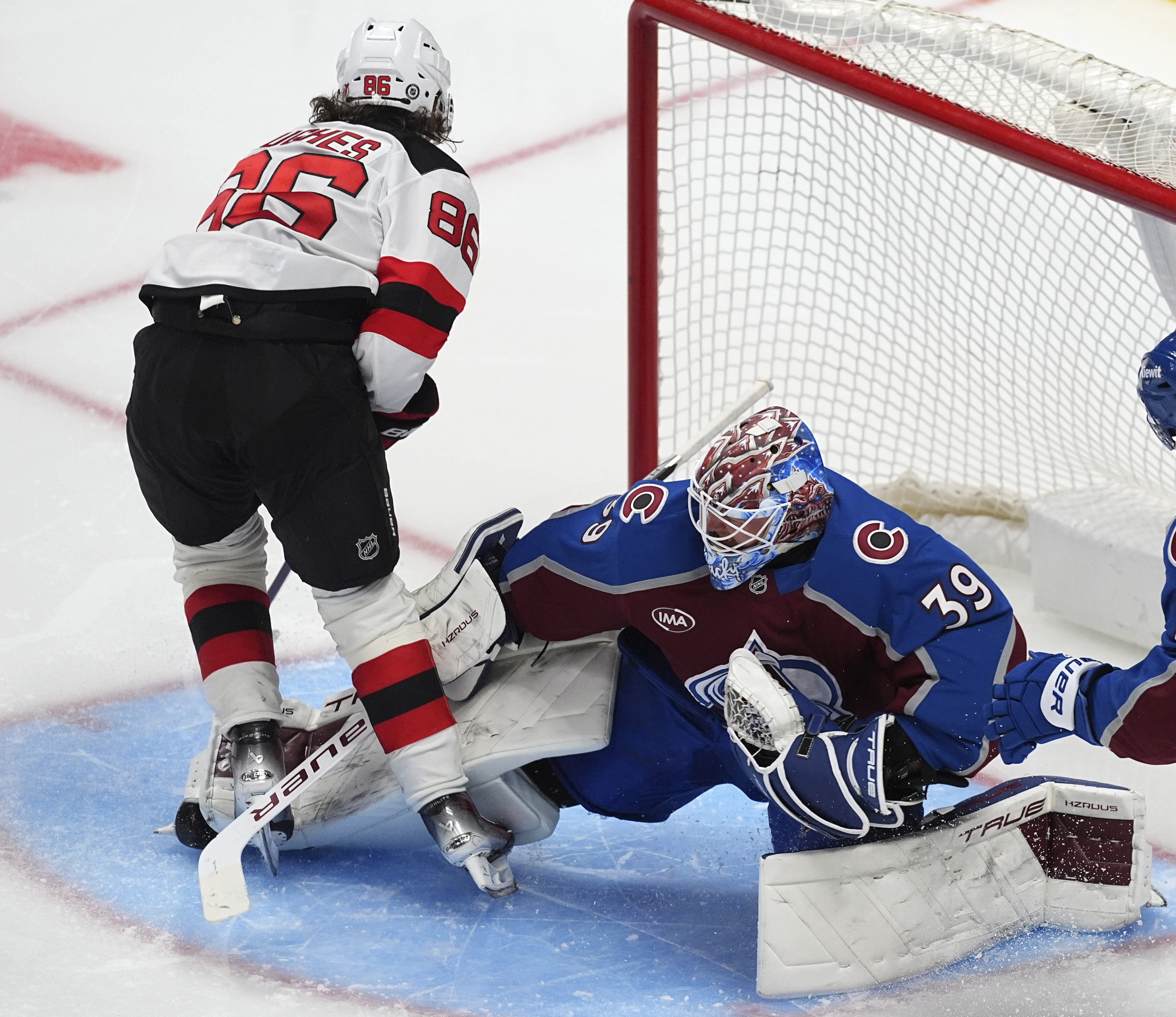 New Jersey Devils center Jack Hughes, left, puts a shot on Colorado Avalanche goaltender Mackenzie Blackwood in the third period of an NHL hockey game Wednesday, Feb. 26, 2025, in Denver. 