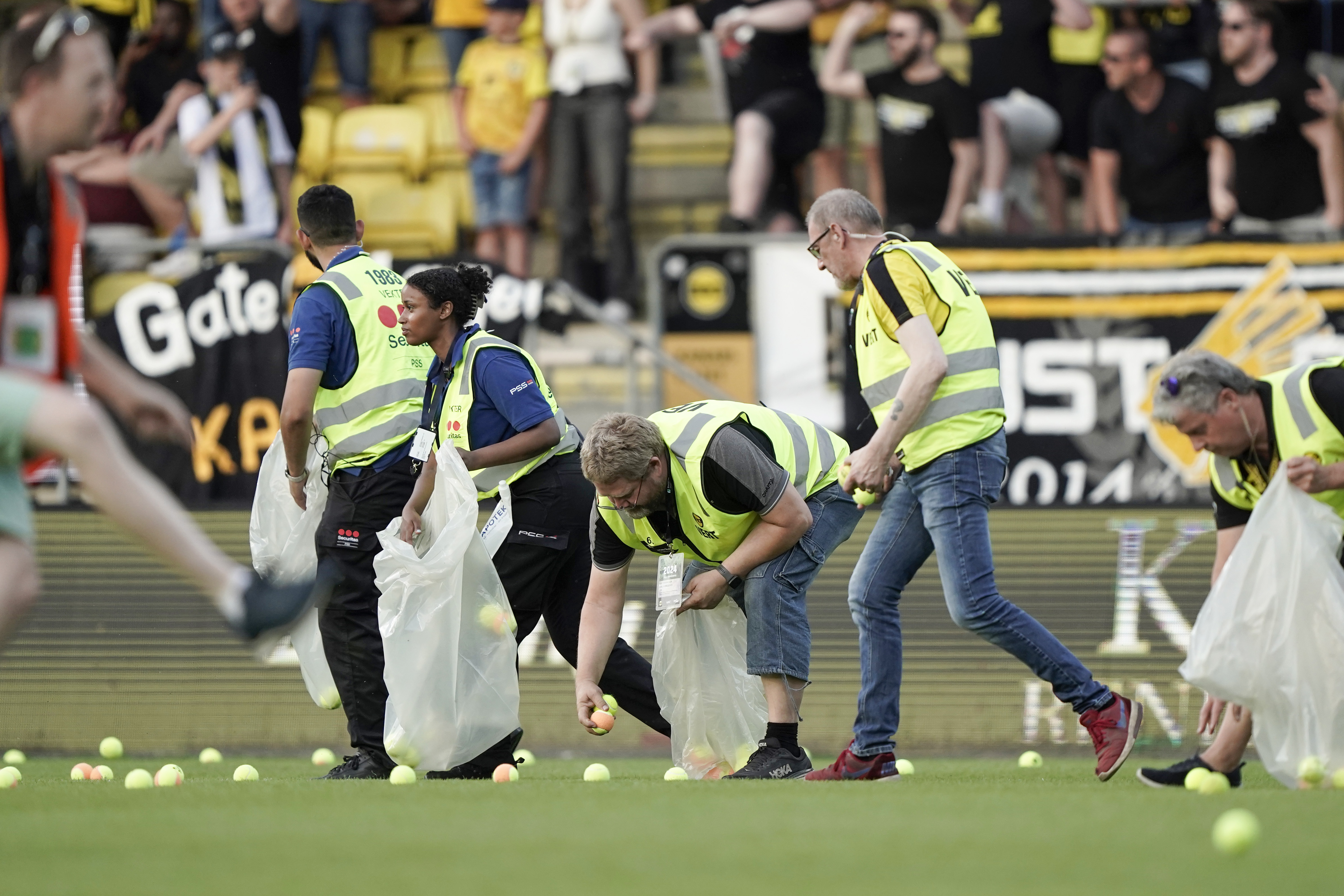 FILE - Pitch crews clean up after the home crowd threw tennis balls onto the pitch in a protest against VAR, shortly after kick-off in soccer match between Lillestrom and KFUM Oslo at Arasen Stadium in Oslo, June 27, 2024. 