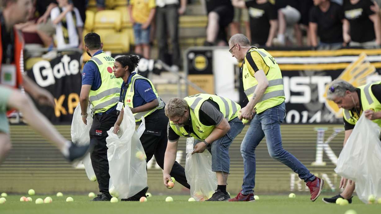 FILE - Pitch crews clean up after the home crowd threw tennis balls onto the pitch in a protest against VAR, shortly after kick-off in soccer match between Lillestrom and KFUM Oslo at Arasen Stadium in Oslo, June 27, 2024.