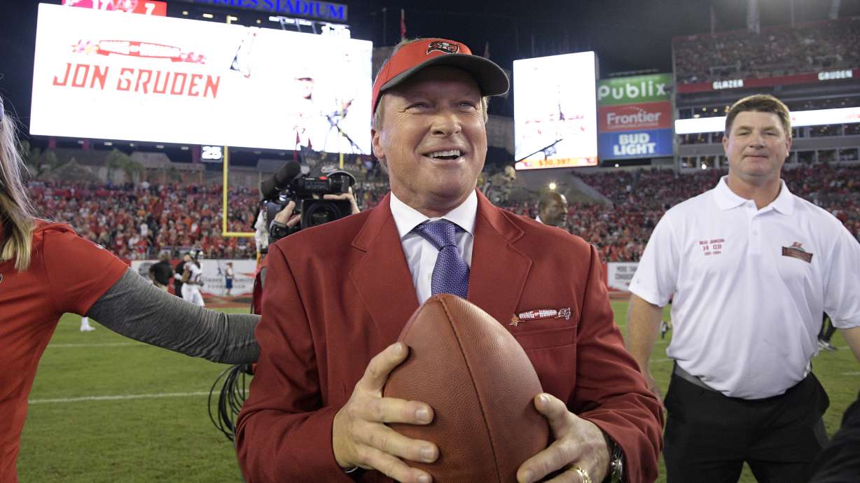FILE - Former Tampa Bay Buccaneers head coach Jon Gruden, center, reacts after being inducted into the Buccaneers Ring of Honor during halftime of an NFL football game against the Atlanta Falcons Monday, Dec. 18, 2017, in Tampa, Fla.