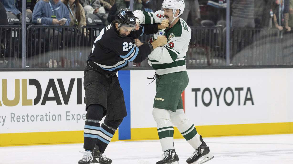 Utah Hockey Club center Jack McBain (22) fights with Minnesota Wild defenseman Jake Middleton (5) during the first period of an NHL hockey game, Thursday, Feb. 27, 2025, in Salt Lake City.
