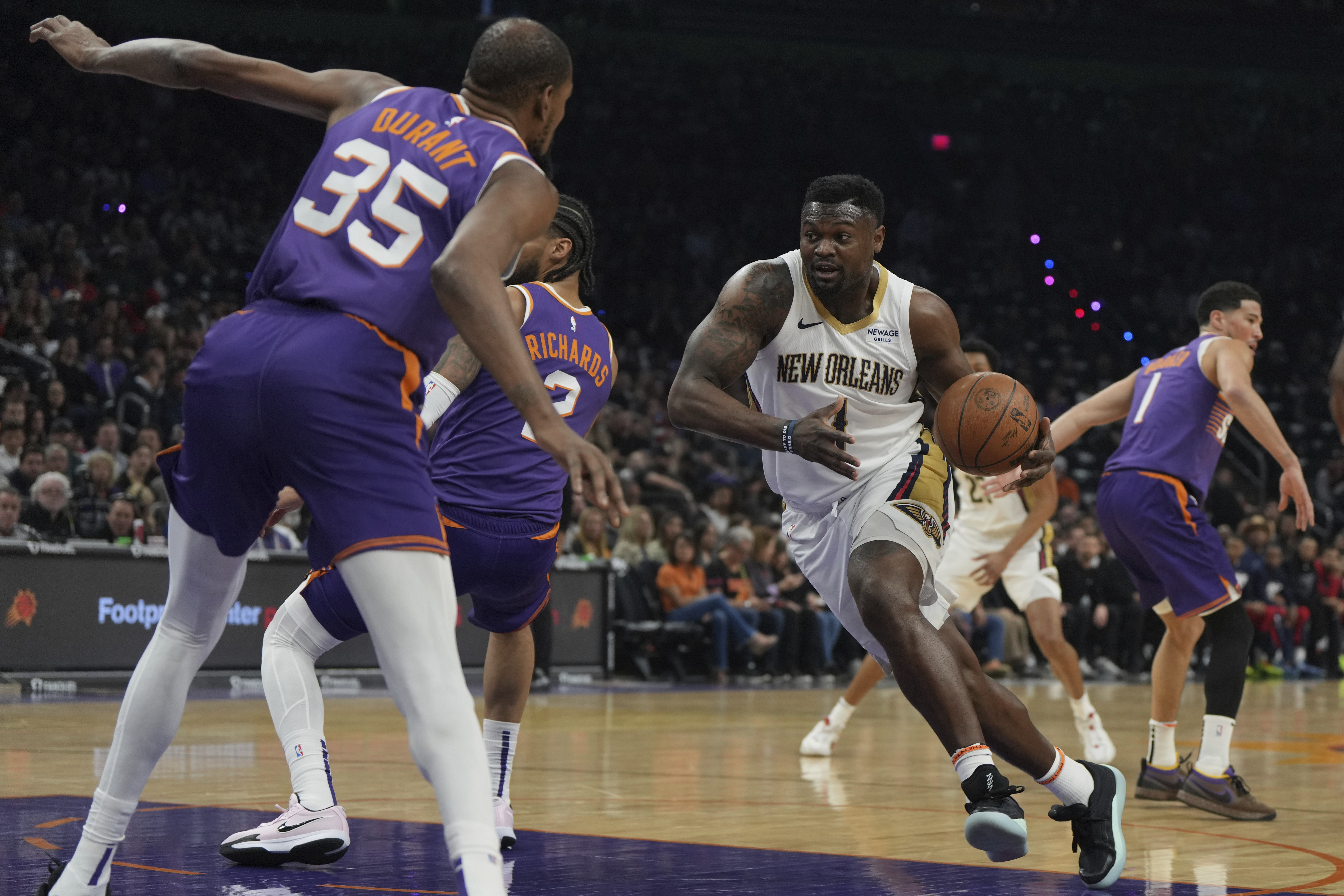 New Orleans Pelicans forward Zion Williamson (1) drives on Phoenix Suns center Nick Richards (2) and forward Kevin Durant during the first half of an NBA basketball game, Thursday, Feb. 27, 2025, in Phoenix. 