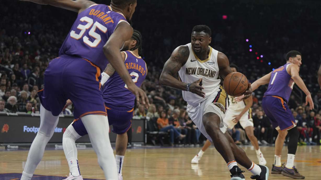 New Orleans Pelicans forward Zion Williamson (1) drives on Phoenix Suns center Nick Richards (2) and forward Kevin Durant during the first half of an NBA basketball game, Thursday, Feb. 27, 2025, in Phoenix.