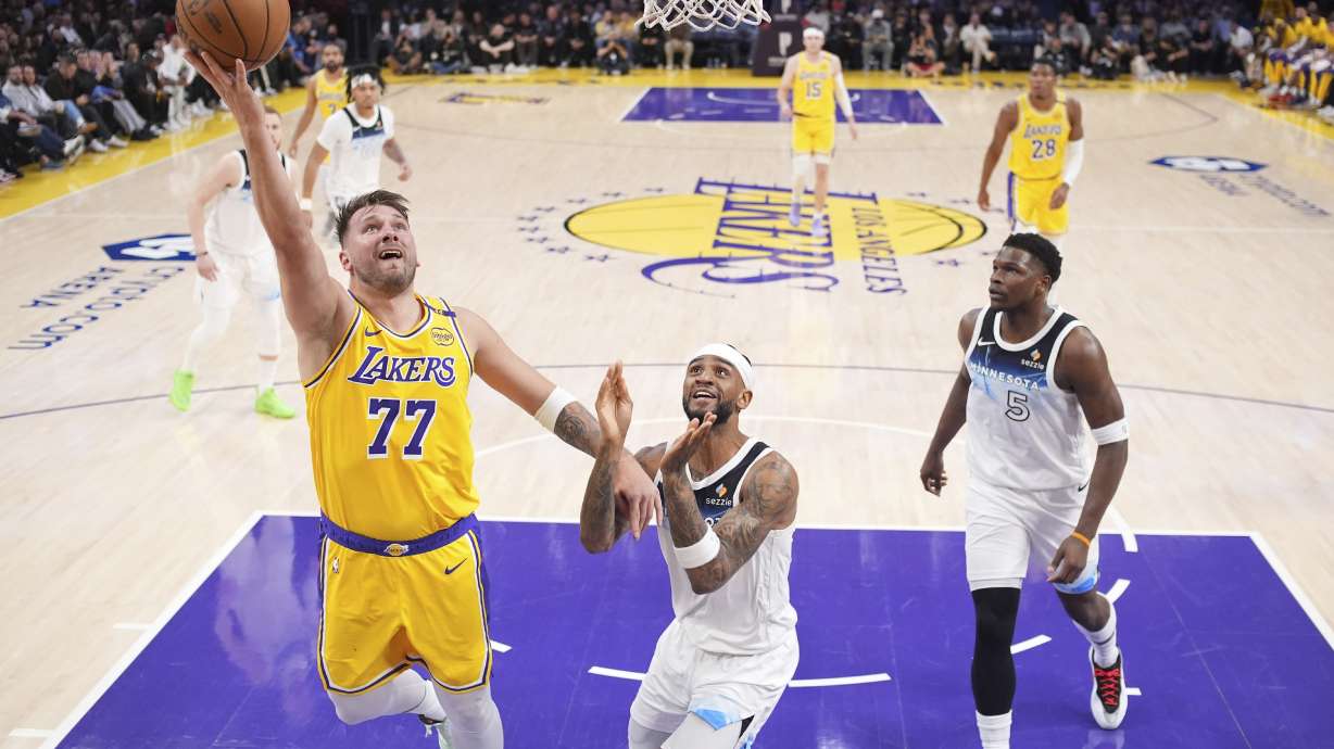 Los Angeles Lakers guard Luka Doncic, left, shoots as Minnesota Timberwolves guard Nickeil Alexander-Walker, center, and guard Anthony Edwards defends during the first half of an NBA basketball game, Thursday, Feb. 27, 2025, in Los Angeles.
